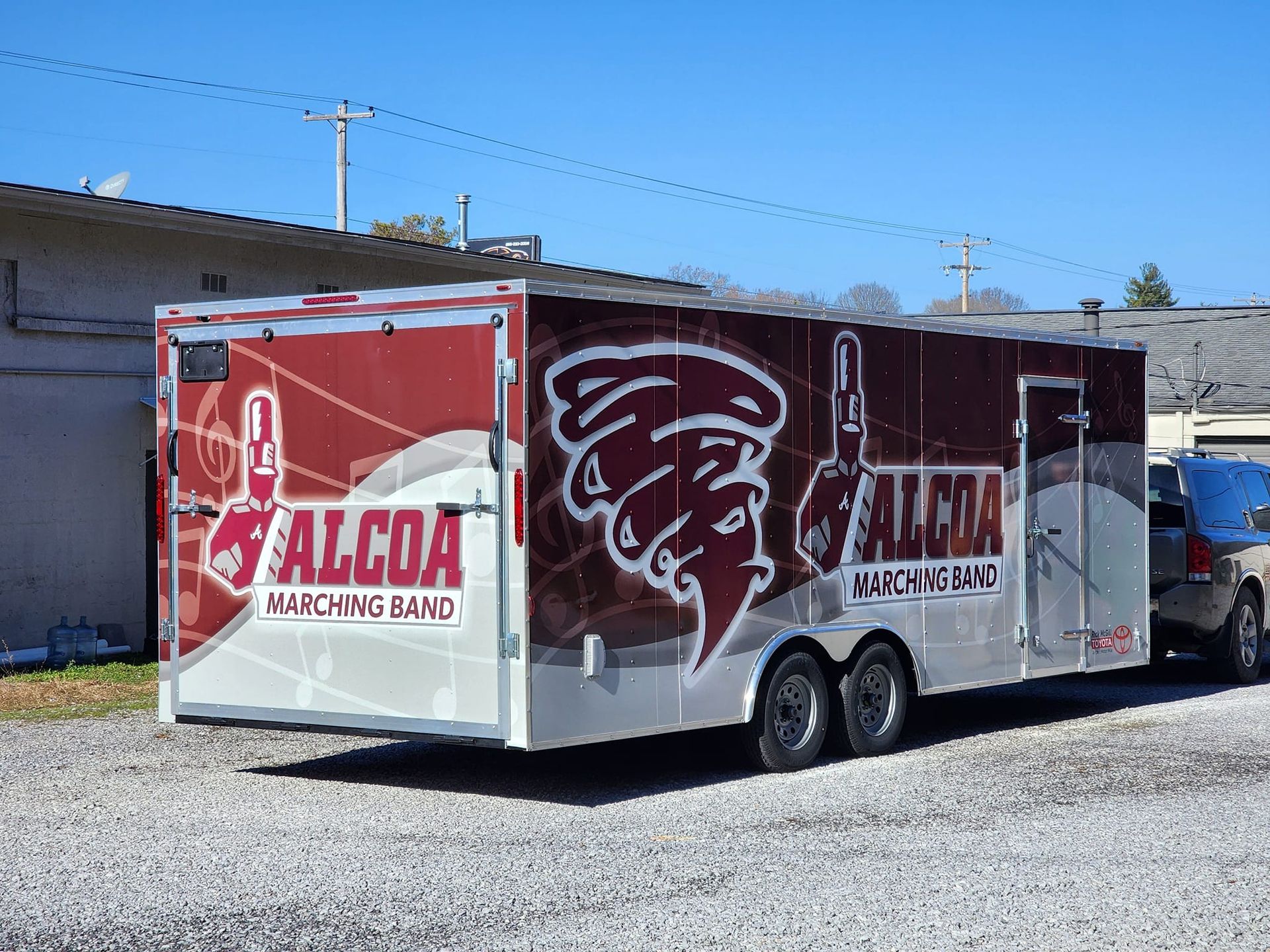 A red and white trailer is parked in a gravel lot.