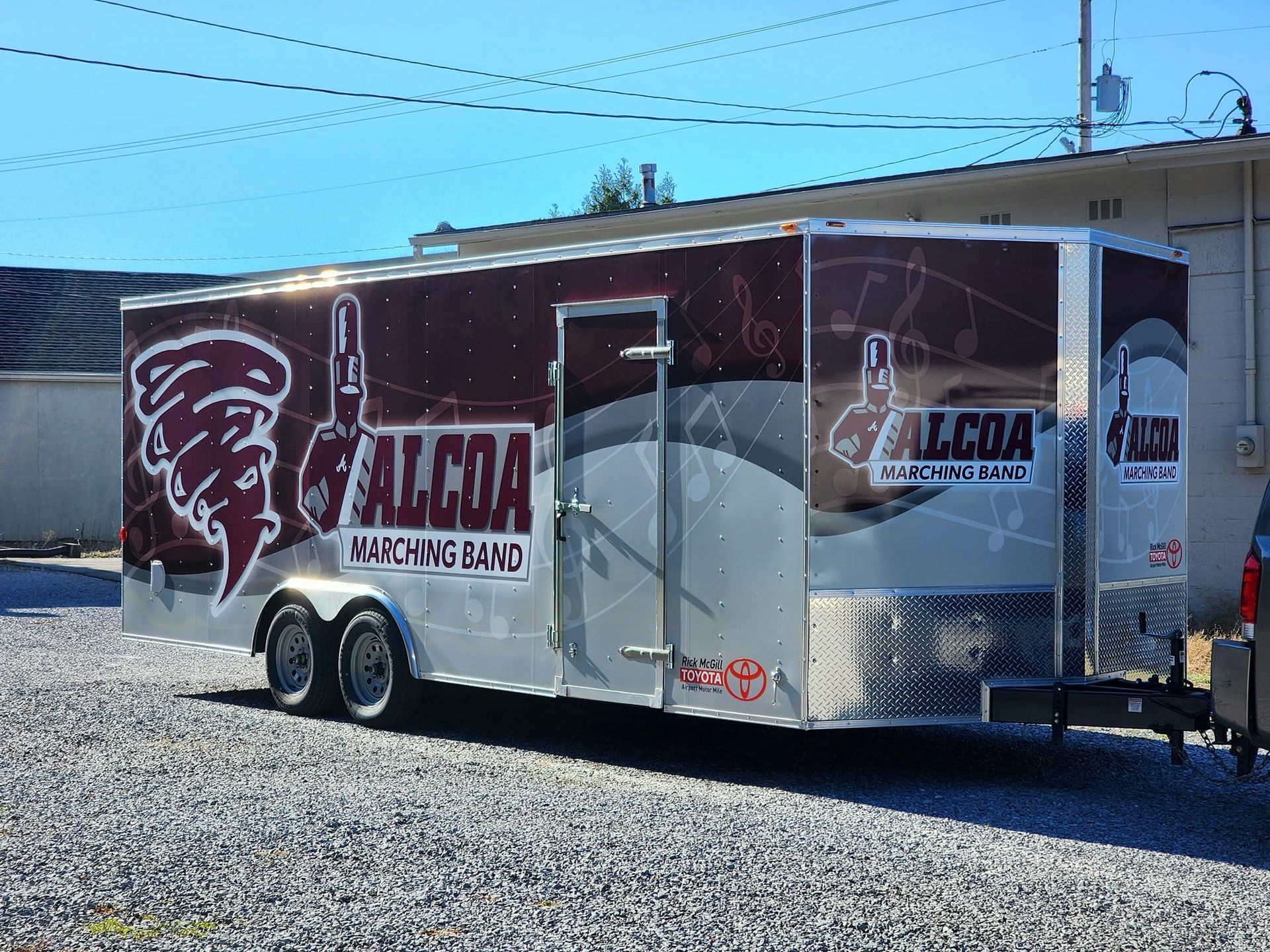 A falcon trailer is parked in a gravel lot