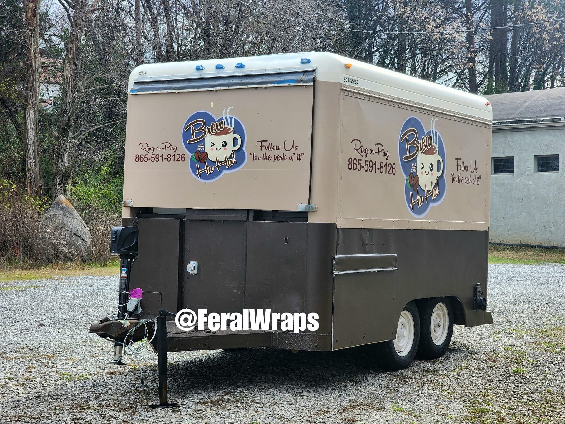 A coffee trailer is parked in a gravel lot.