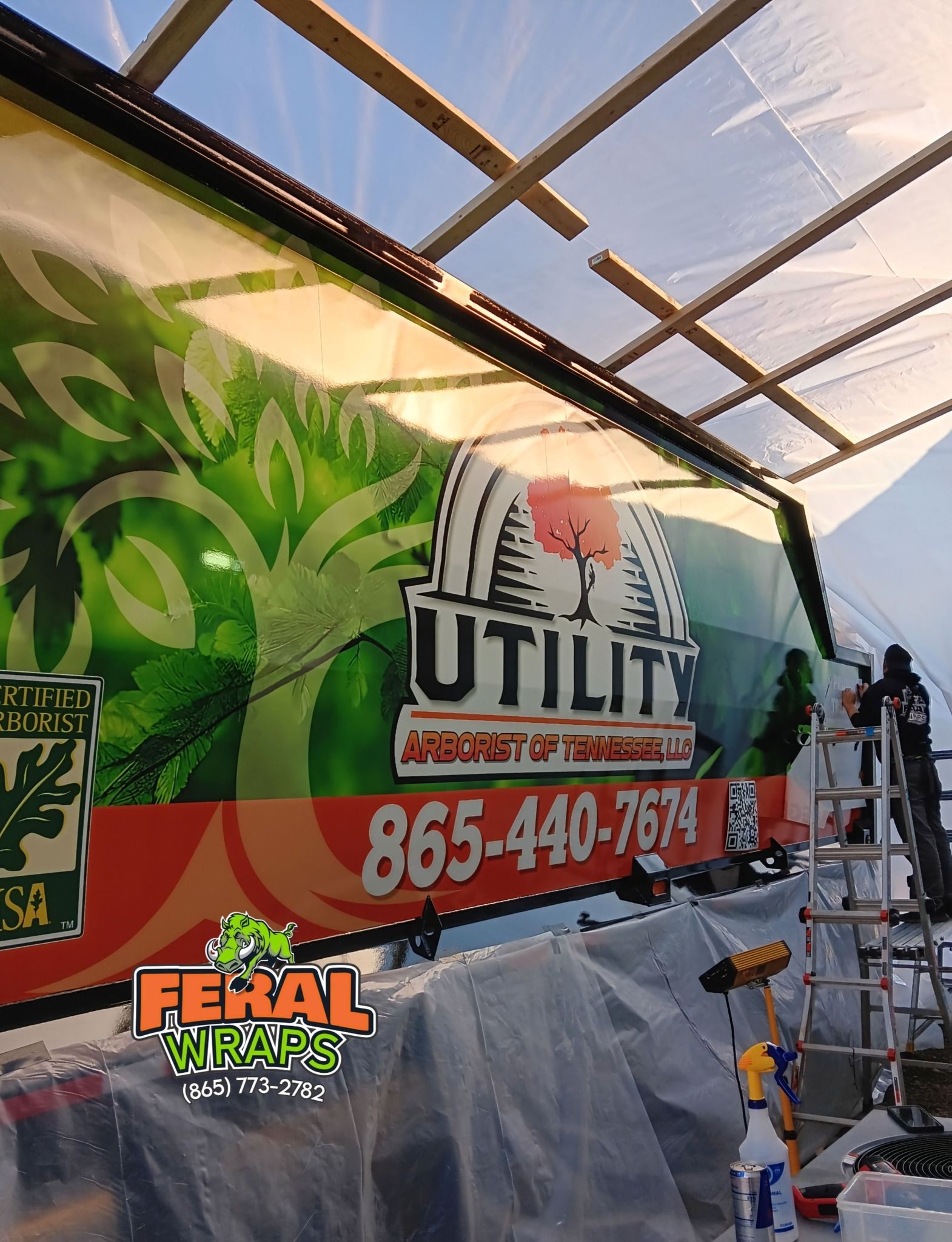 A utility truck is being painted in a greenhouse