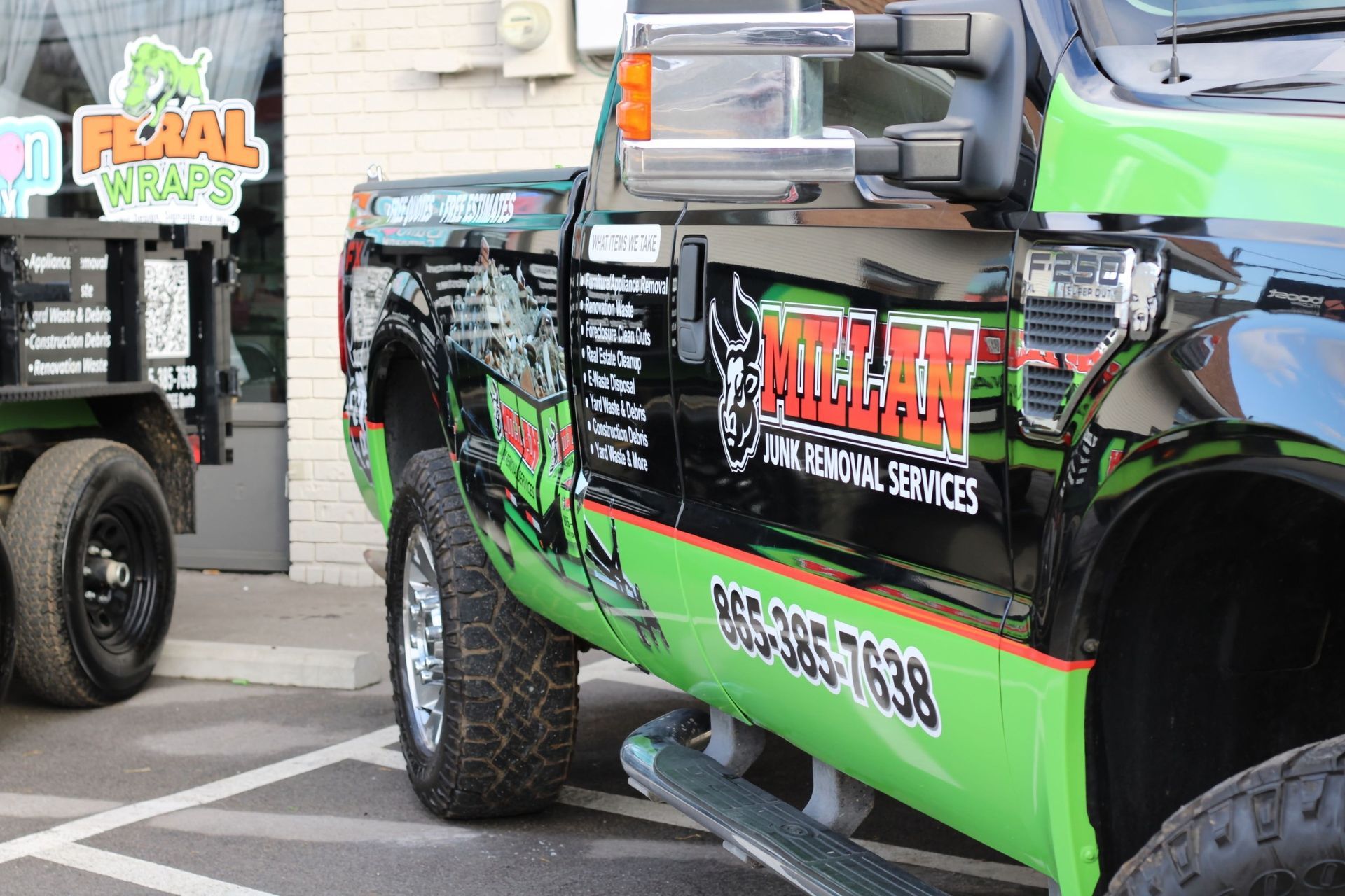 A green and black truck is parked in a parking lot.