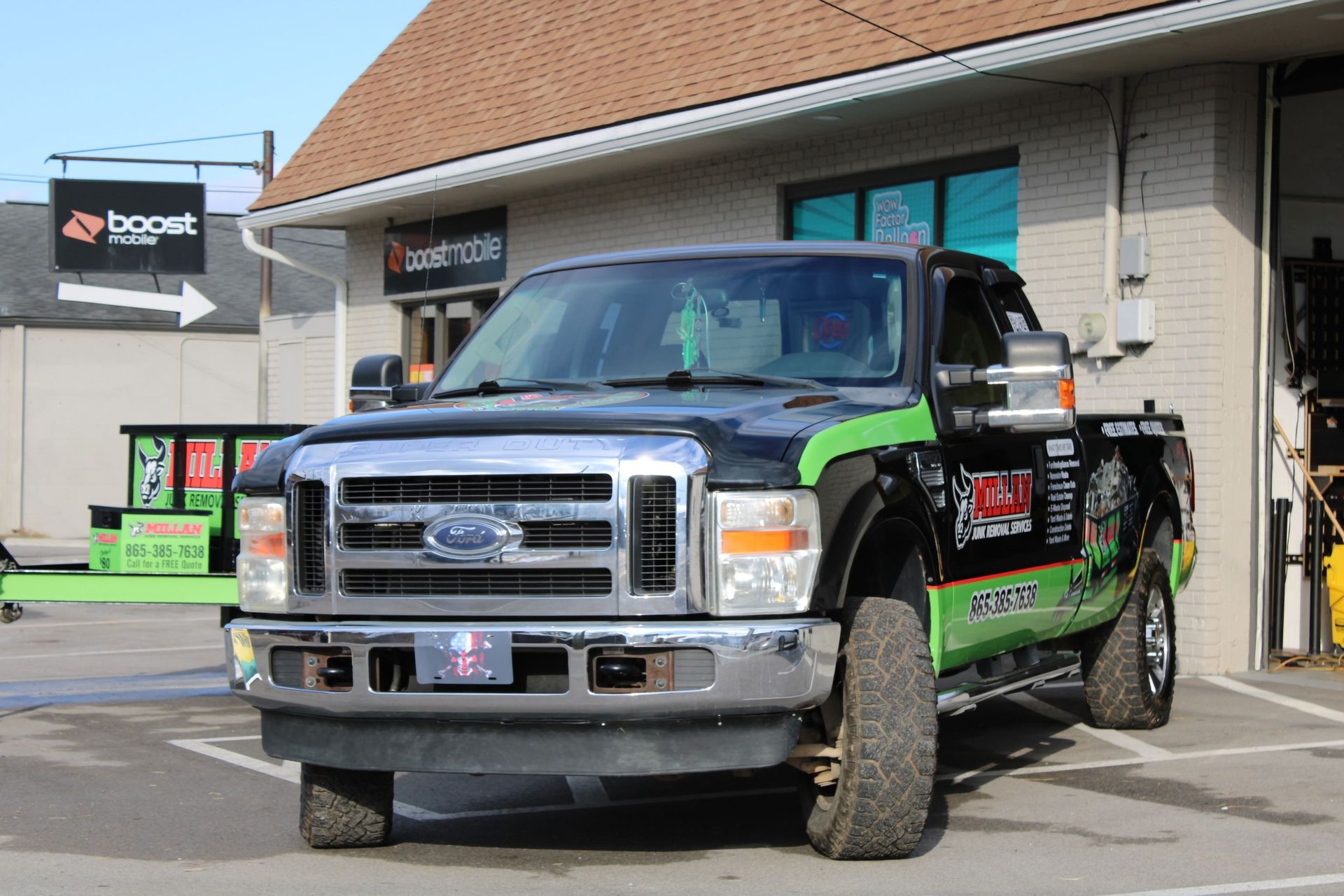 A black and green ford truck is parked in front of a building.