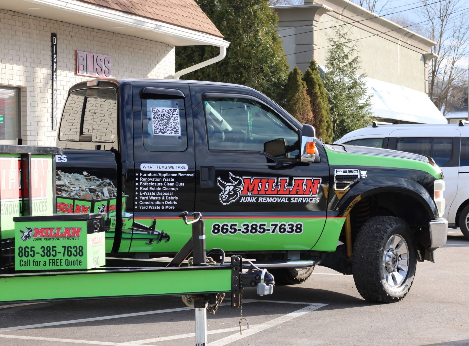 A black and green tow truck is parked in a parking lot