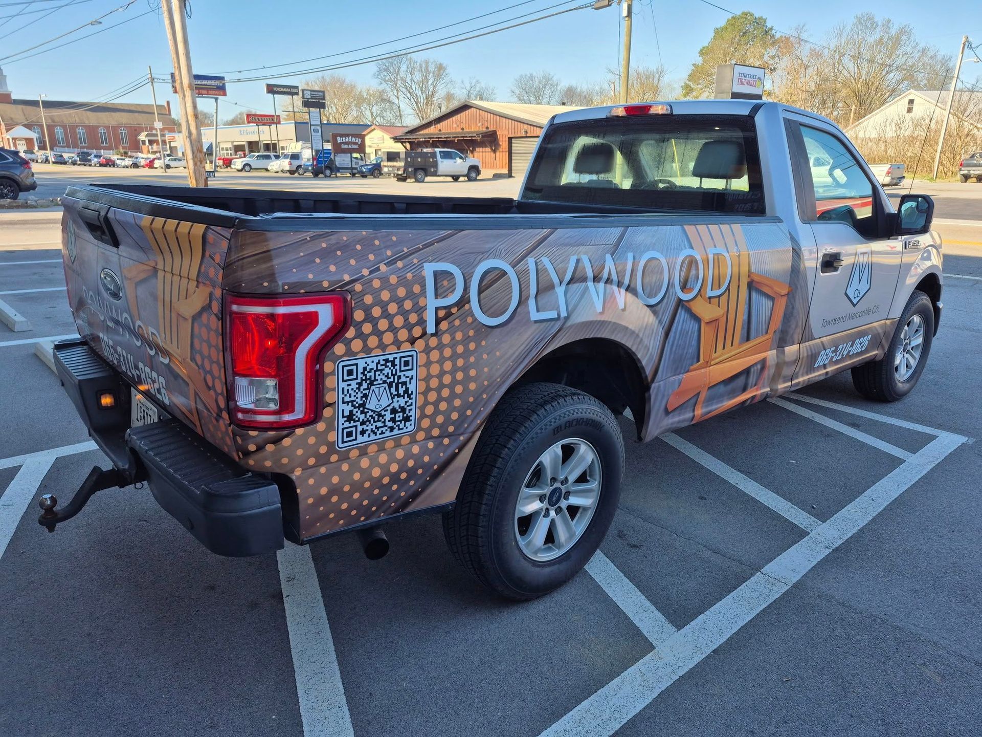 A truck with a wrap on it is parked in a parking lot.