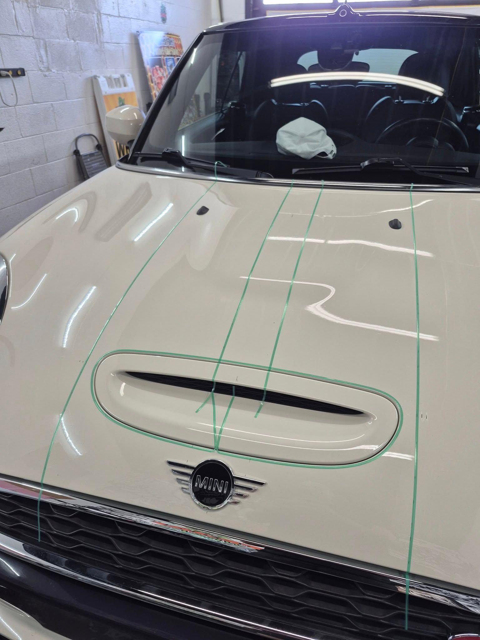A white mini cooper with green lines on the hood