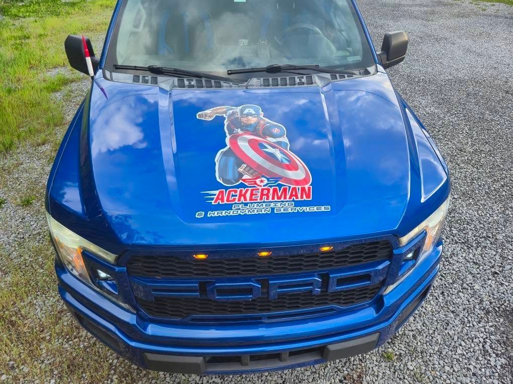A blue ford truck with a captain america sticker on the hood