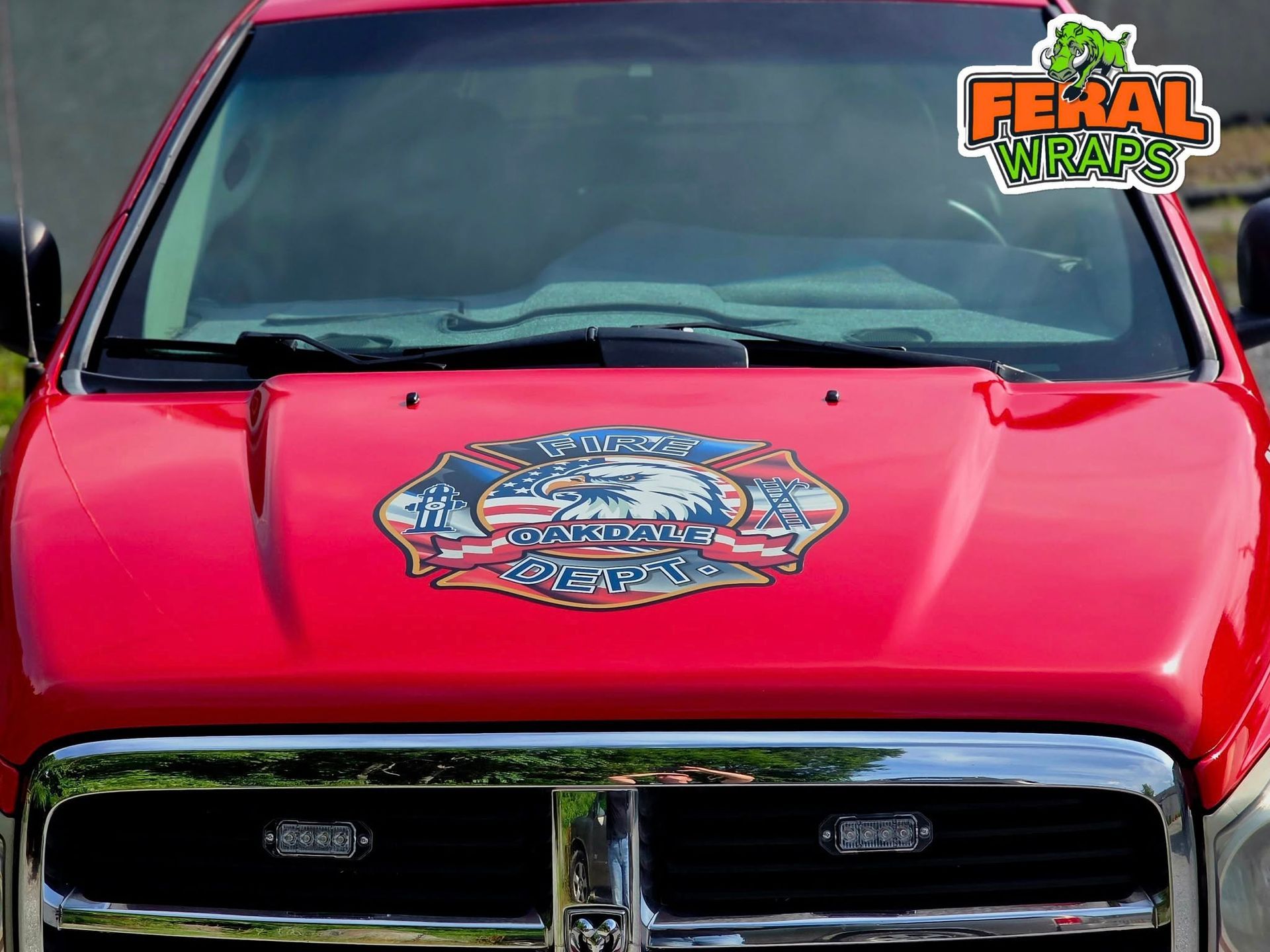 A red truck with a sticker on the hood that says feral wraps