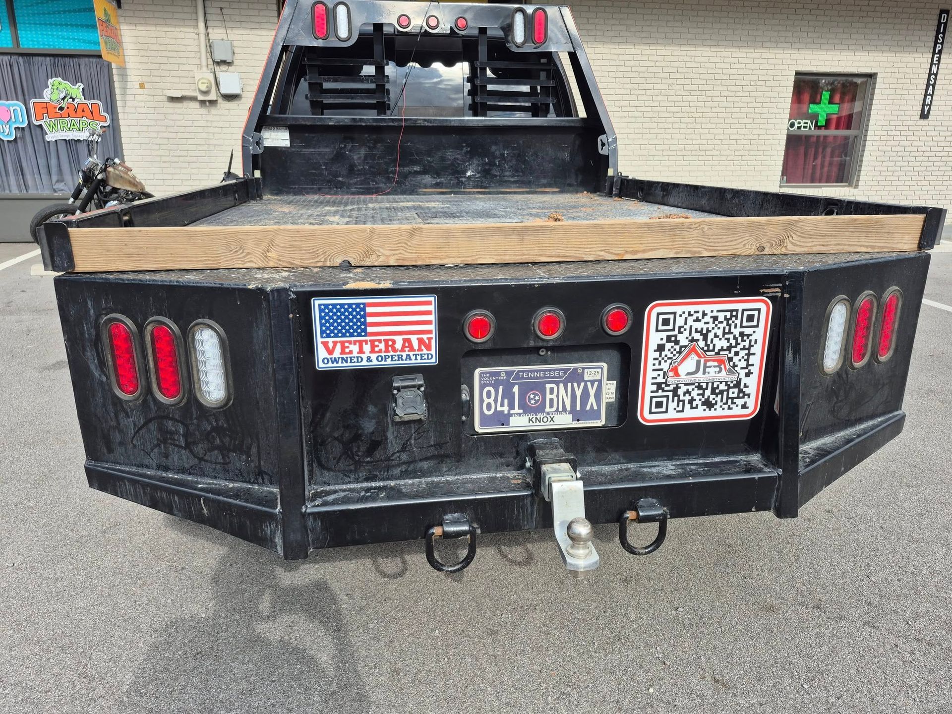 Black flatbed truck bed with a Veteran sticker, license plate, and QR code sticker.