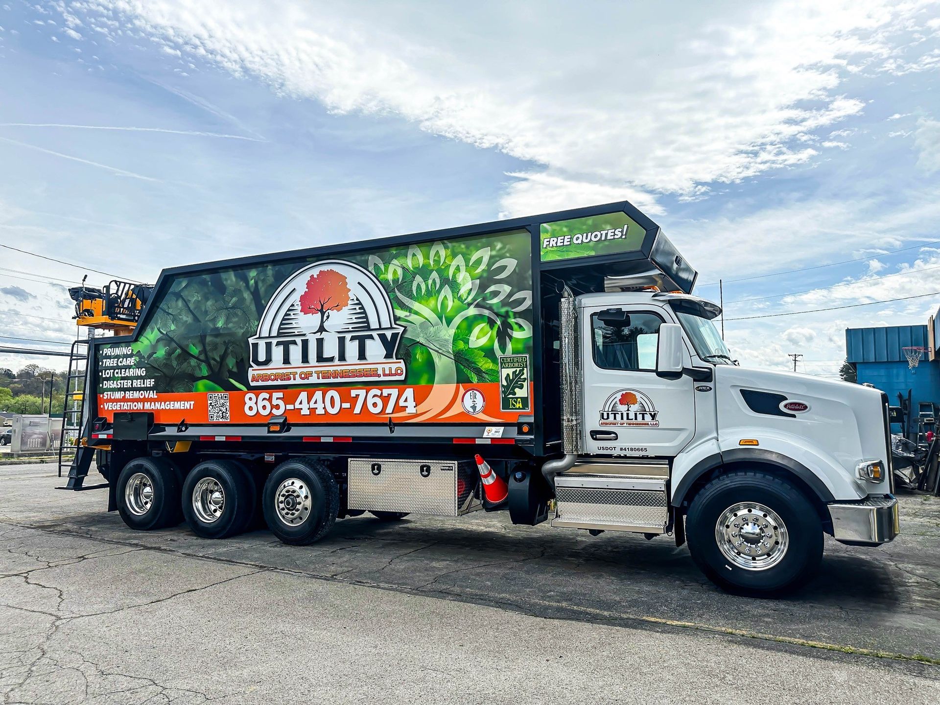 Utility truck with tree and leaf graphics, orange accents, and phone number 865-440-7674.