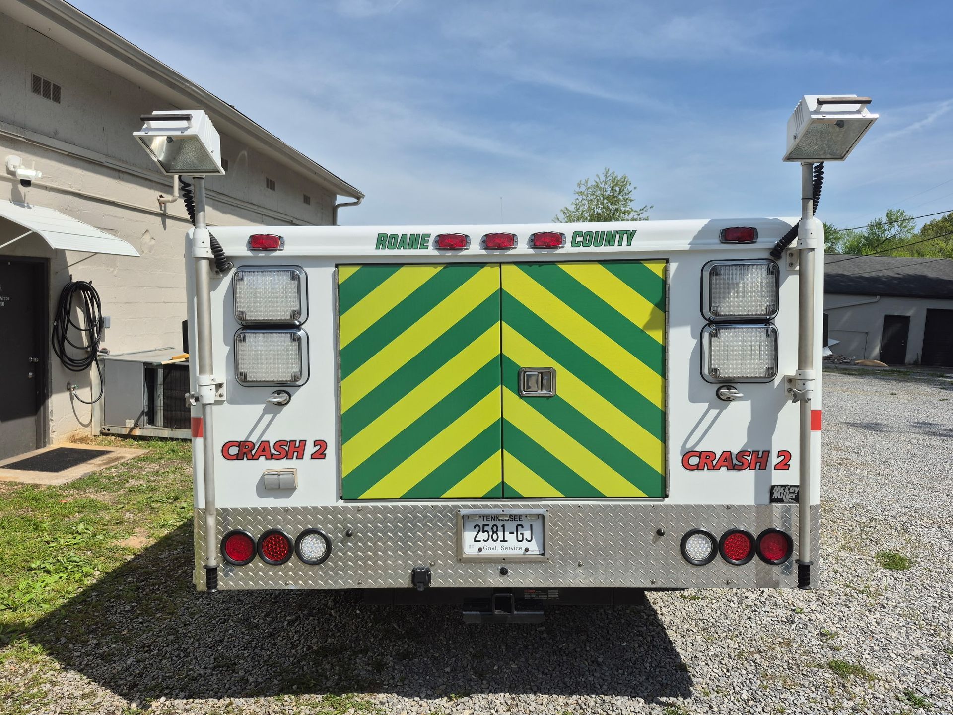 A white truck with green and yellow stripes on the back