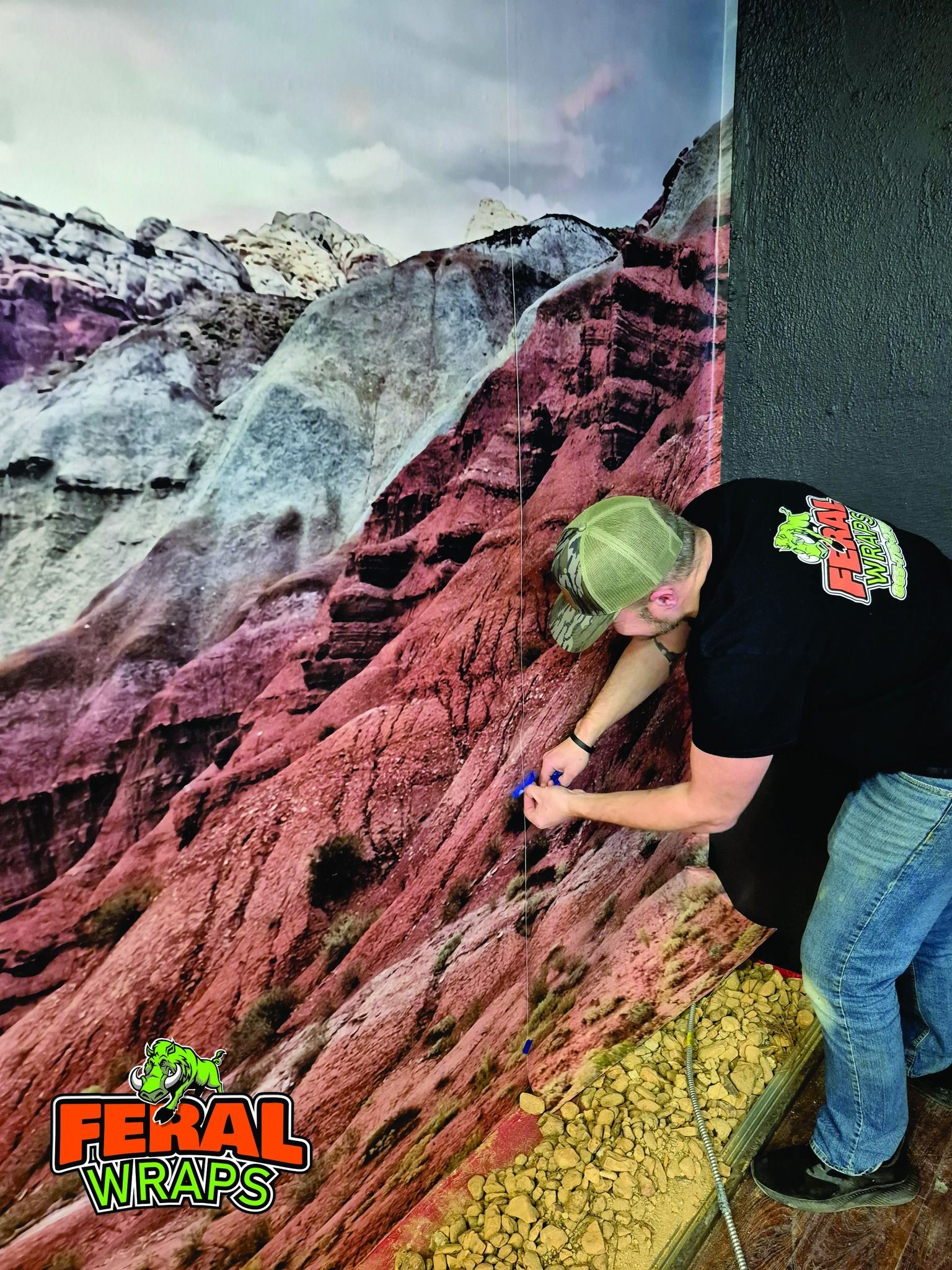 Person applying vinyl mountain scene to a wall. Red, tan, and white rock formations.