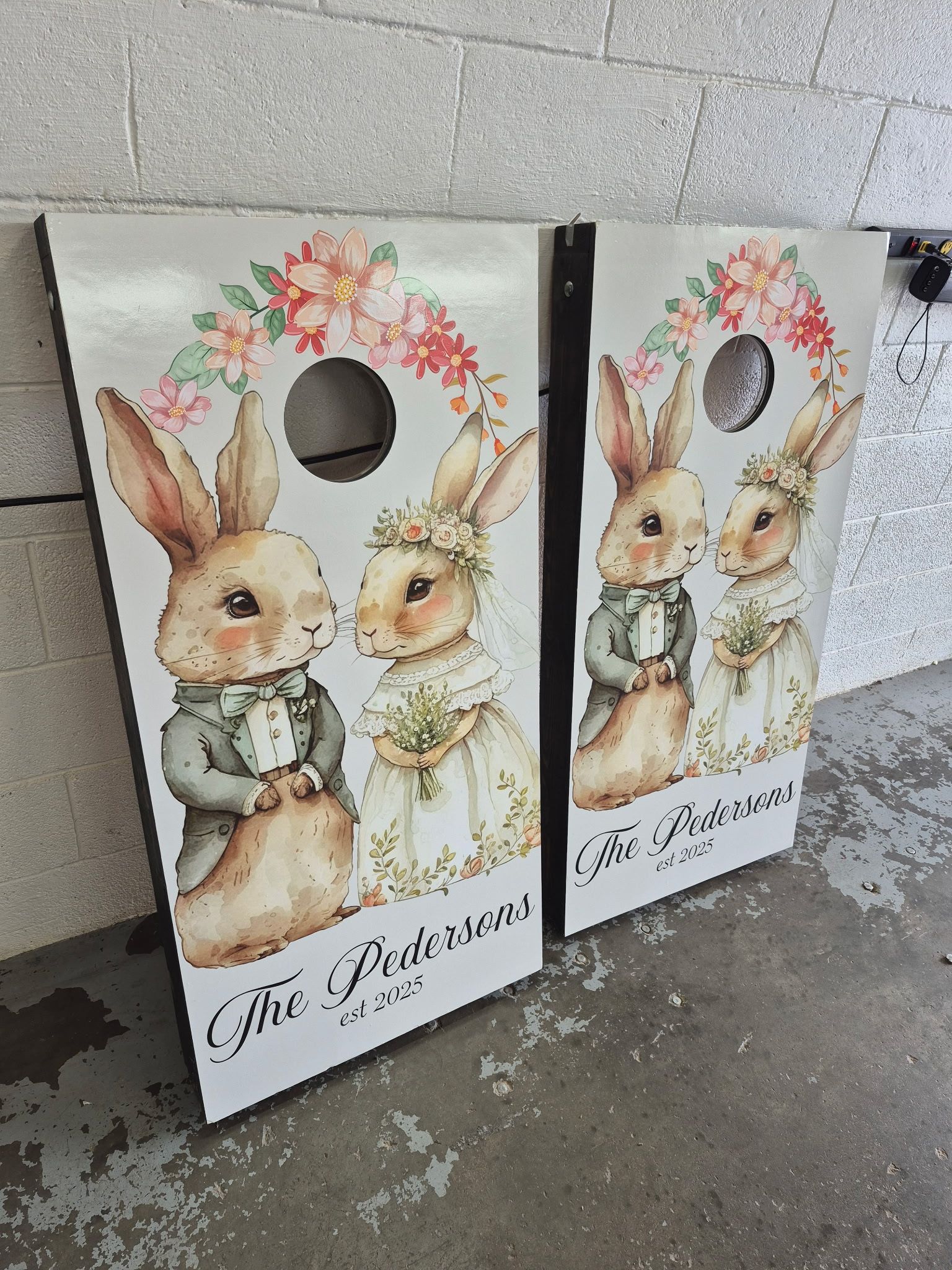 Two cornhole boards with rabbits on them are sitting on the ground.