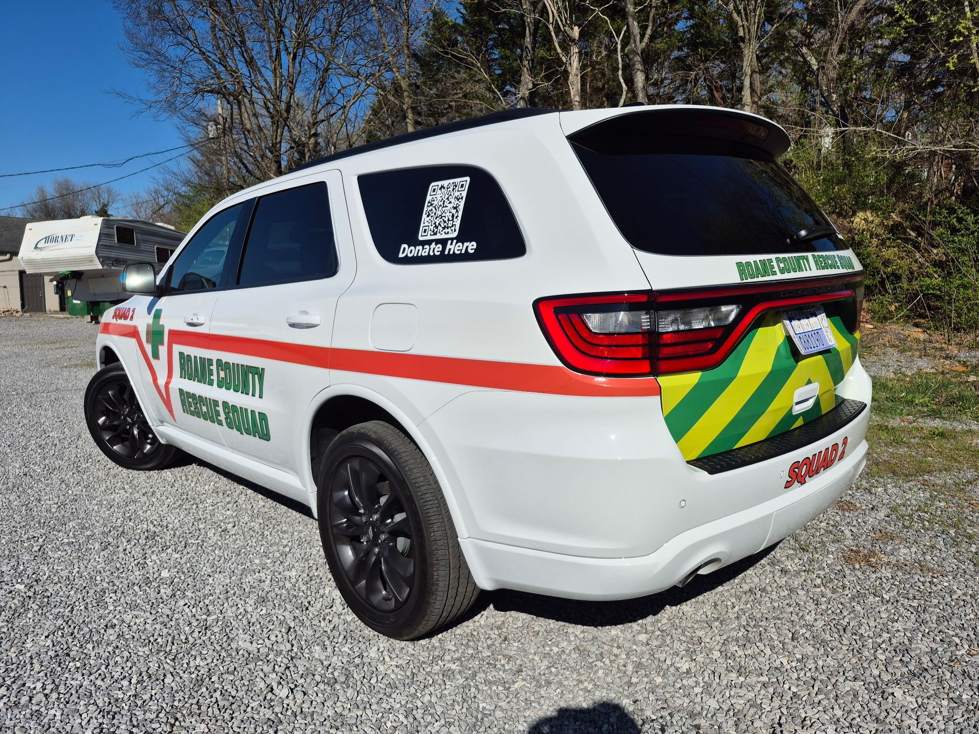 A white dodge durango police car is parked in a gravel lot.