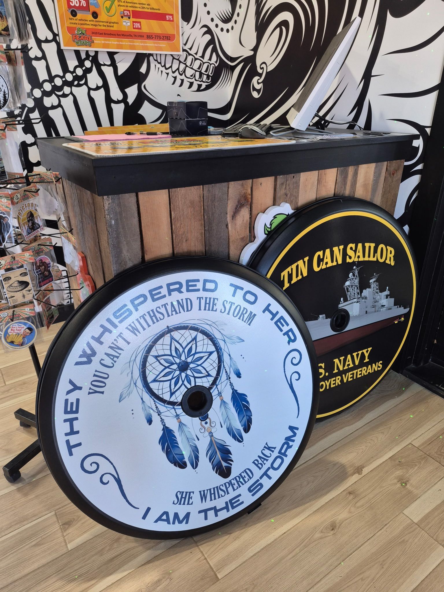 Two spare tire covers with artwork and text displayed in a shop.