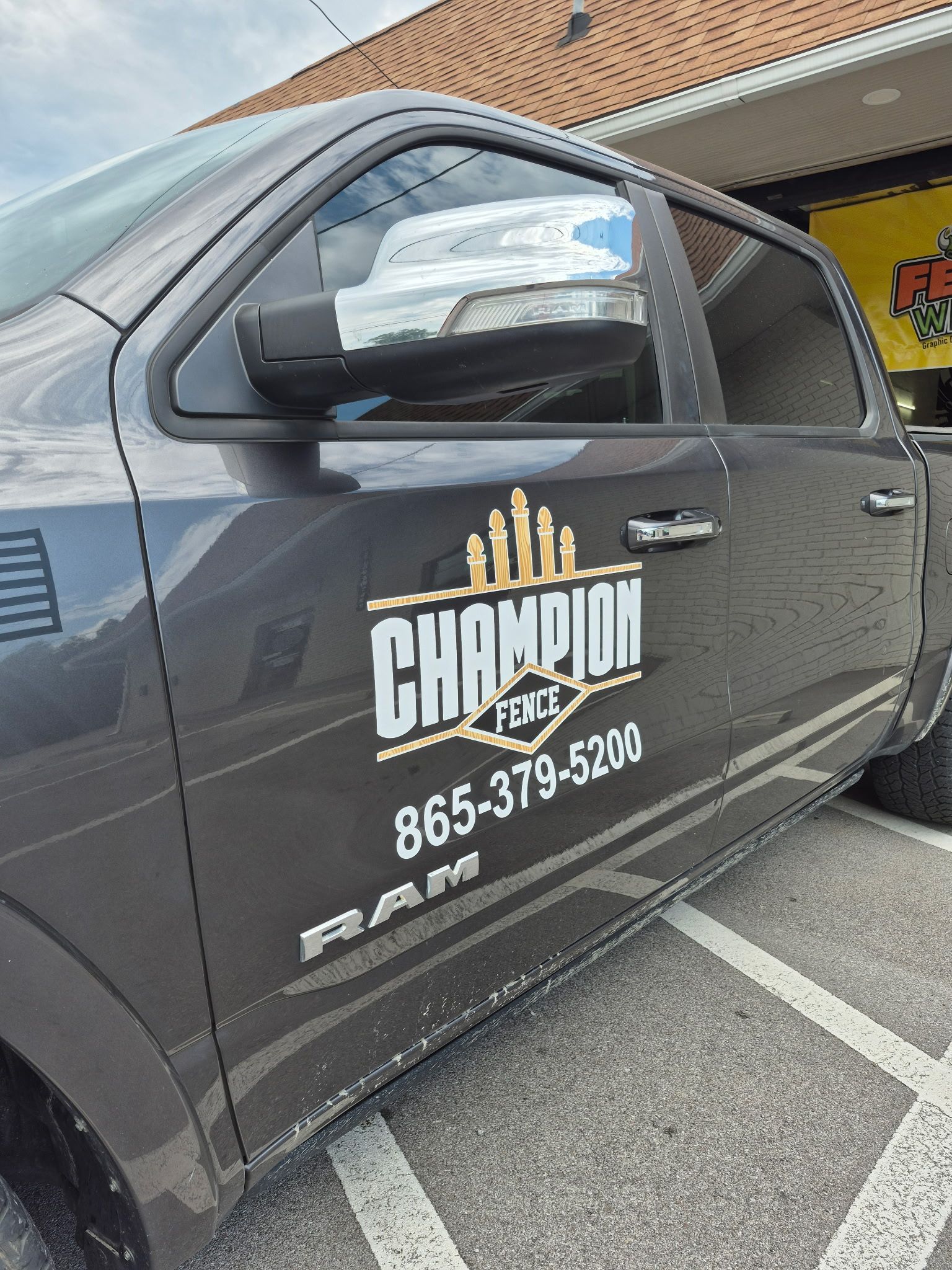 Gray Champion Fence truck with logo and phone number parked outside.