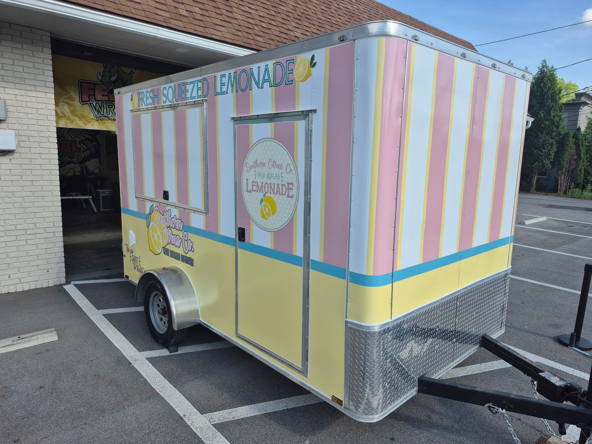 A pink and yellow striped trailer is parked in a parking lot.