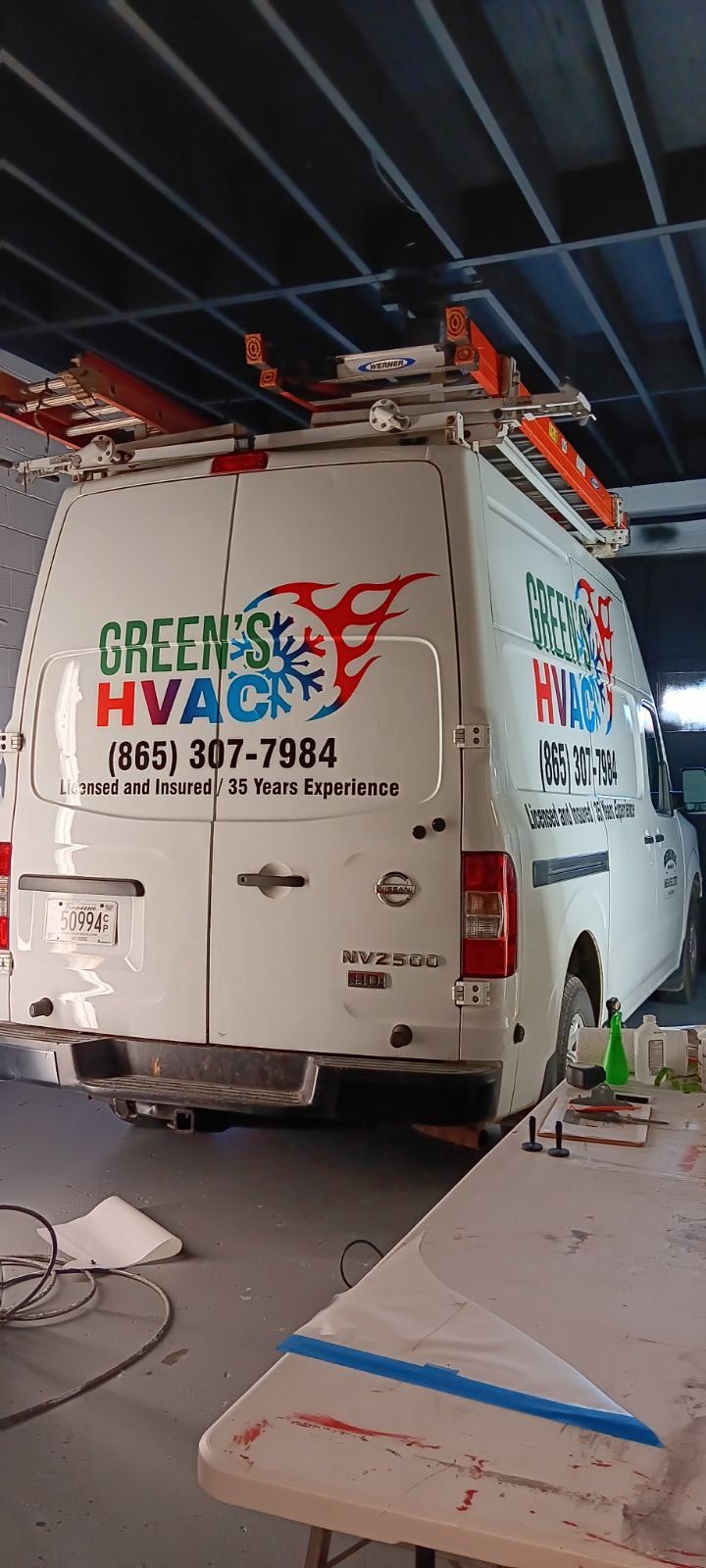 A white van is parked in a garage next to a table.