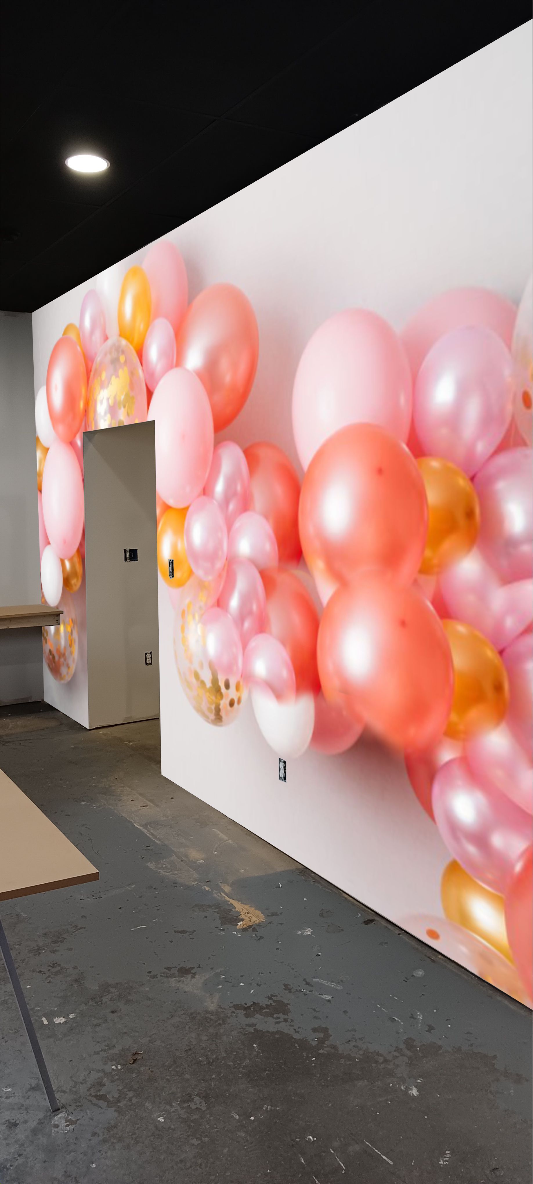 A bunch of pink and orange balloons are hanging on a wall.