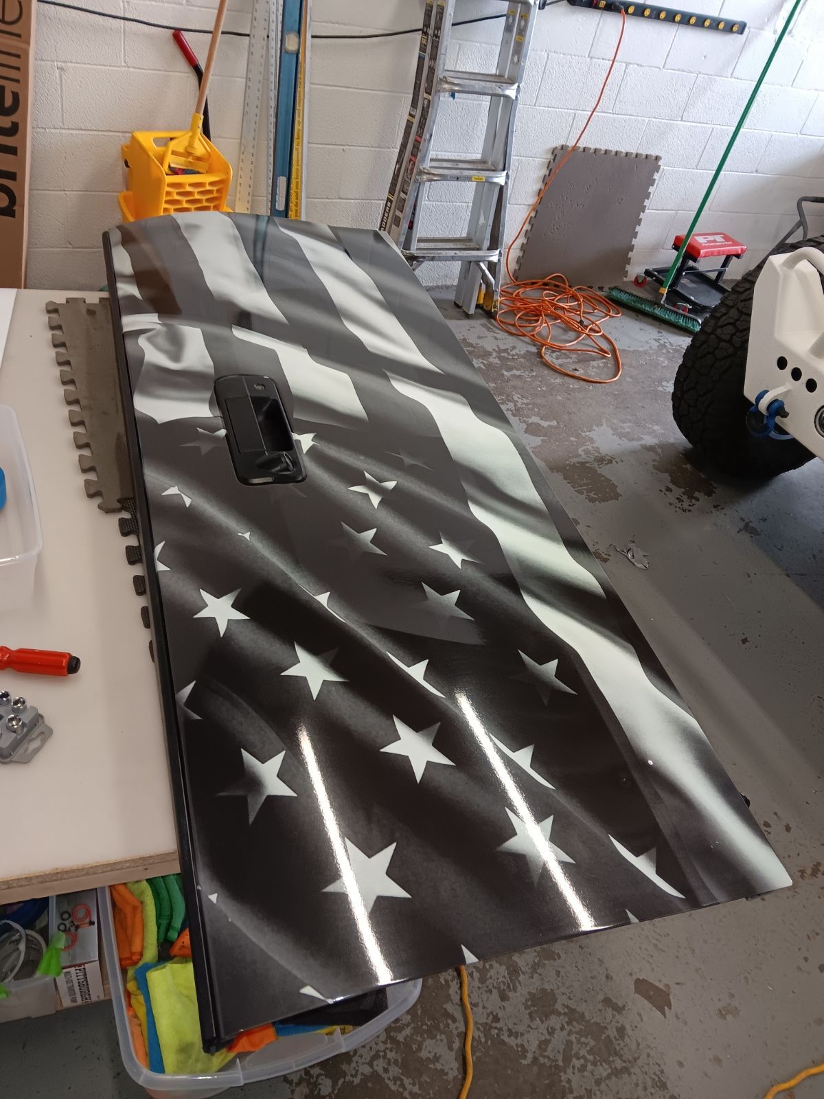 A black and white american flag is painted on a door in a garage.