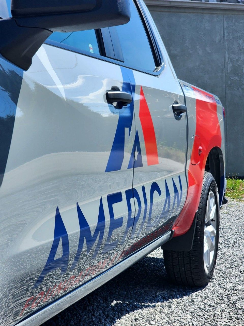 A silver american truck is parked on gravel