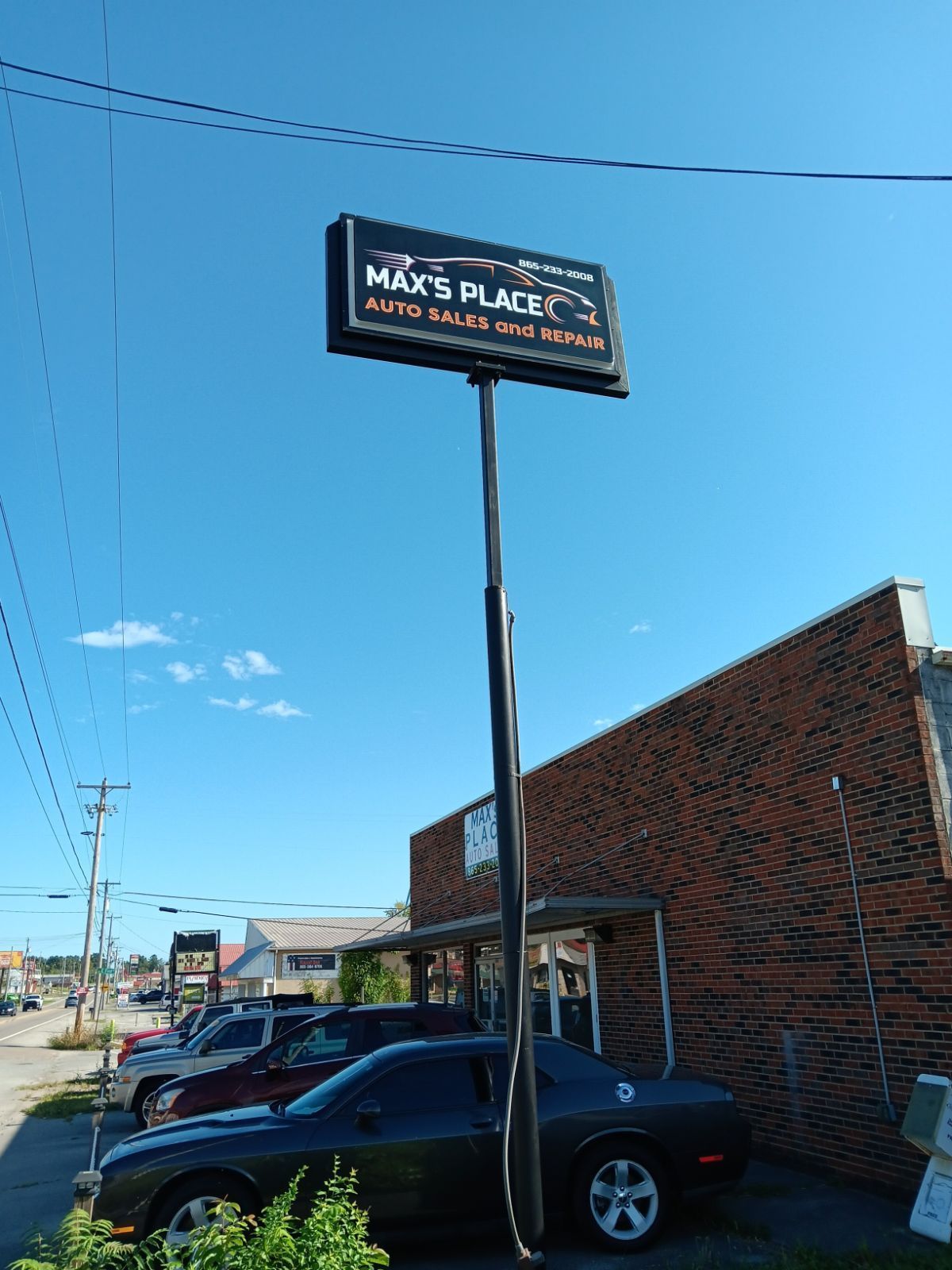 A black car is parked in front of a sign that says max 's place