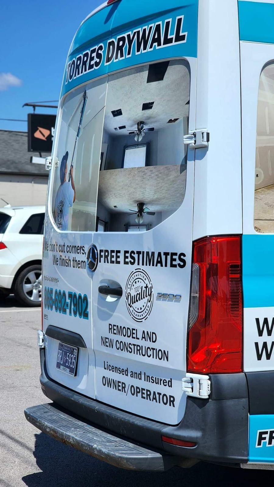 A blue and white van is parked in a parking lot.