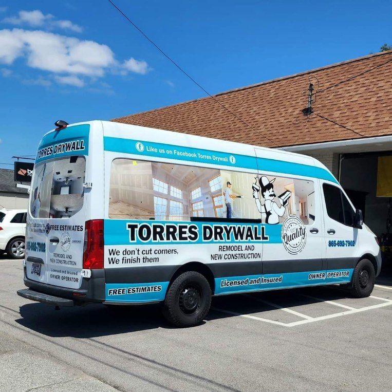 A van that says torres drywall is parked in front of a building