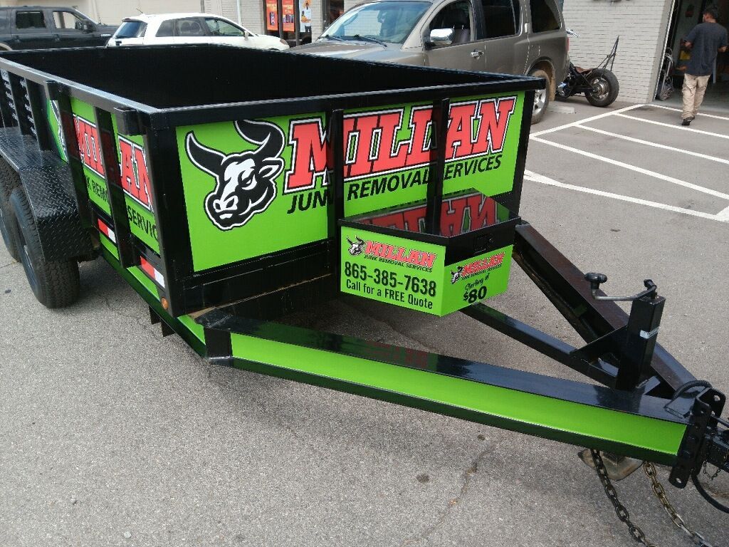 A green and black trailer with a bull on it is parked in a parking lot.