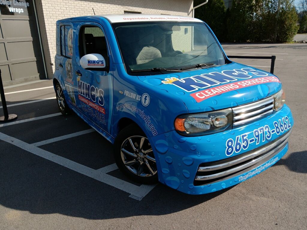 A blue and white van is parked in a parking lot.