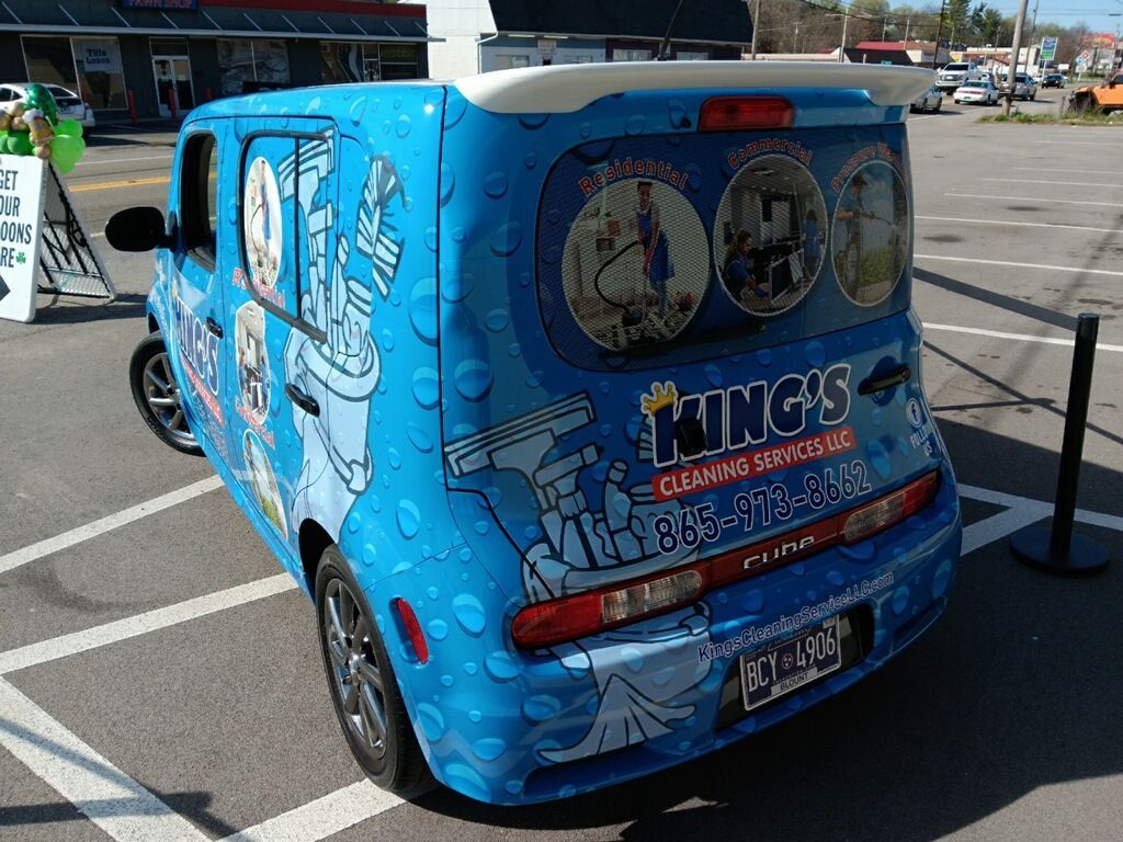A blue van with the word kings on the back is parked in a parking lot