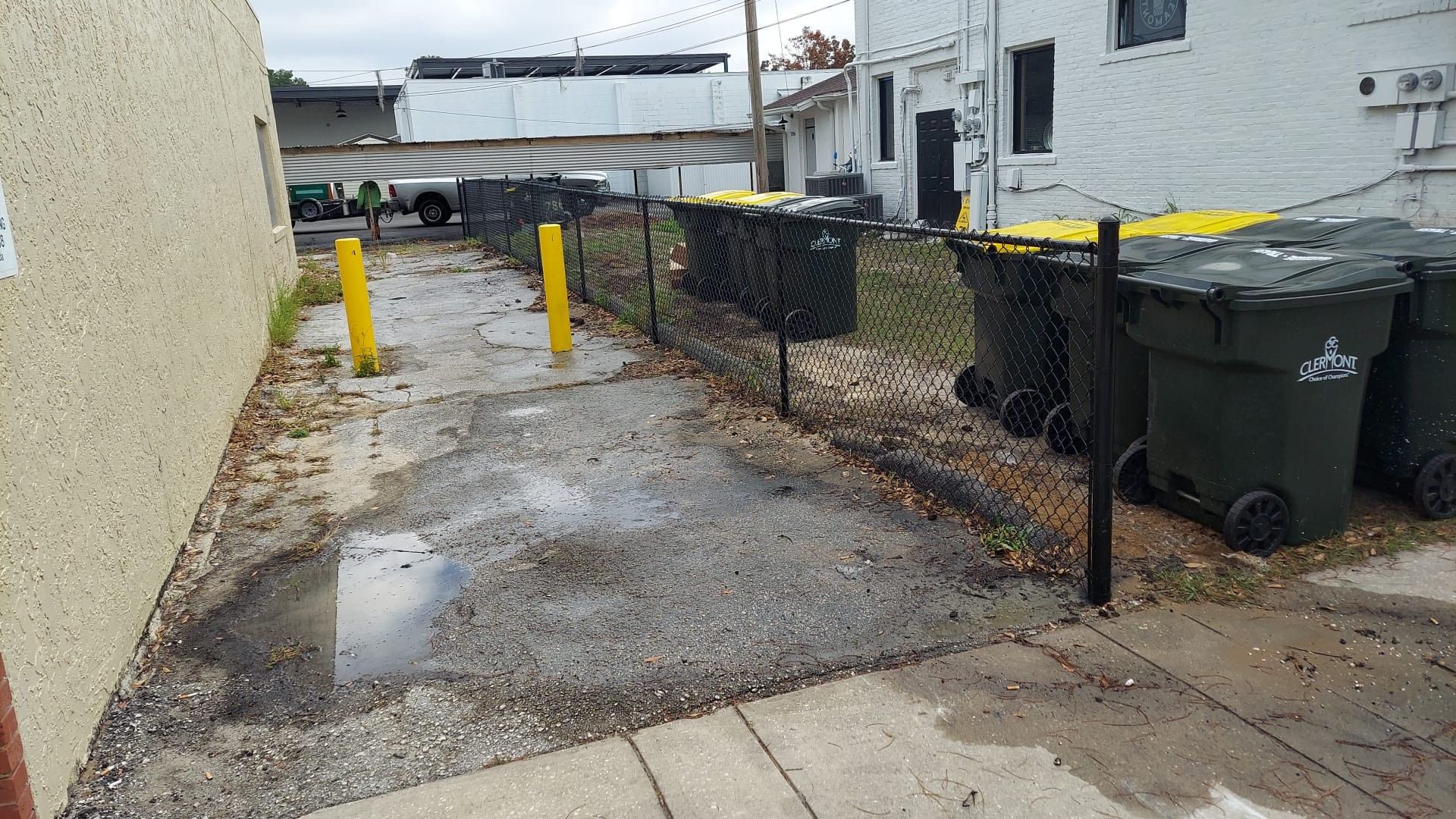 A row of trash cans are lined up next to a fence