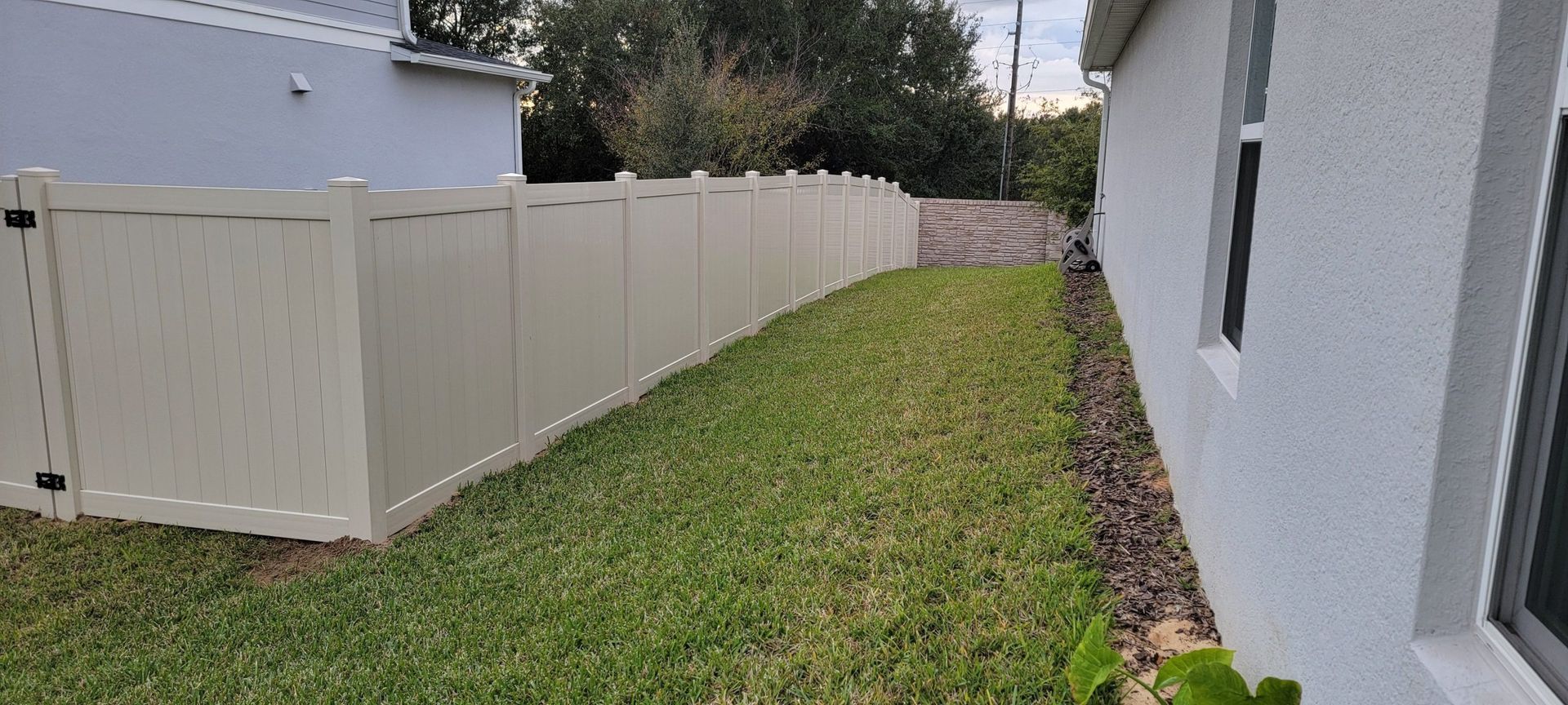There is a white fence in the backyard of a house.