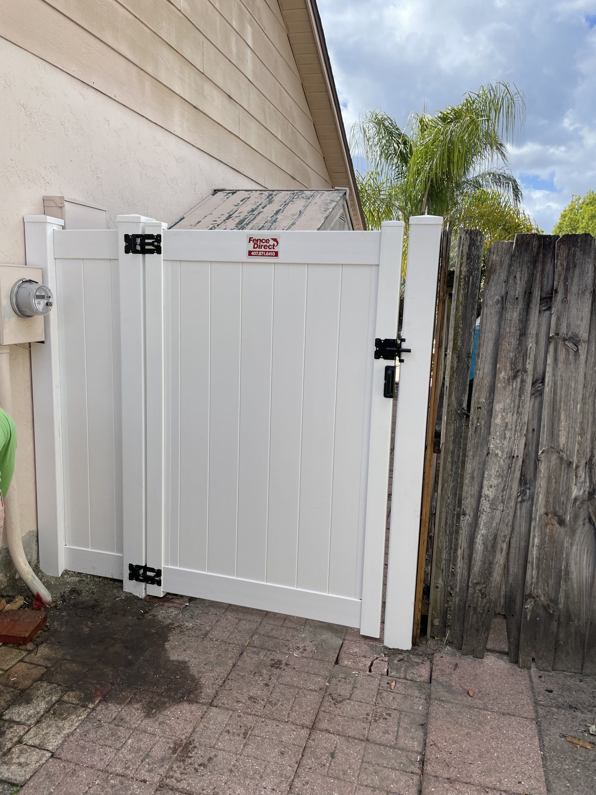 A white fence with a gate in front of a house.