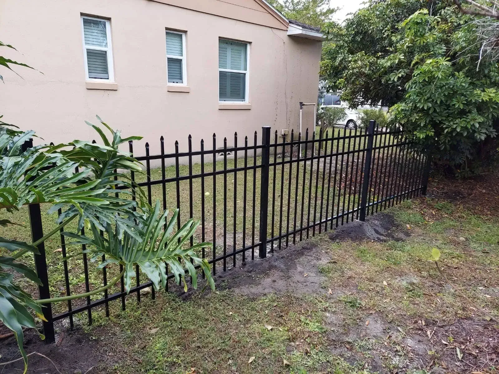 A black metal fence is in front of a house.