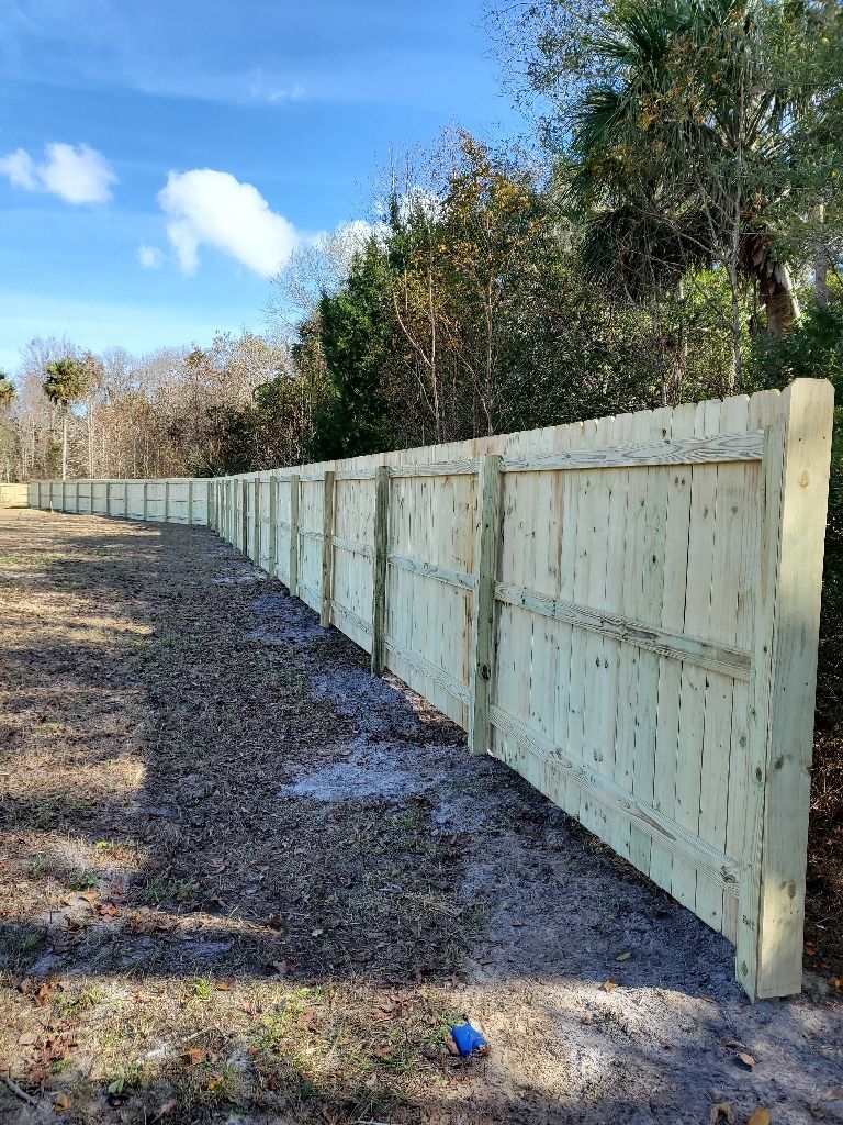 A long wooden fence is sitting in the middle of a dirt field.