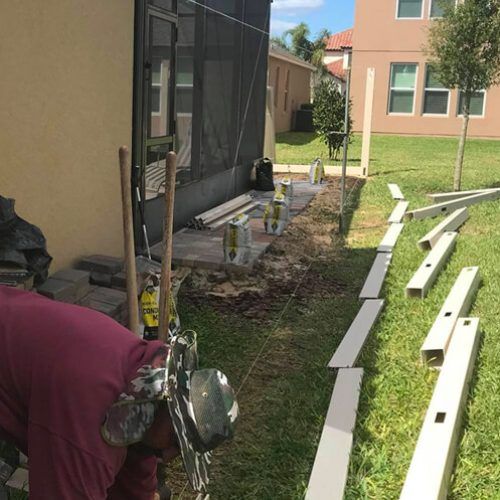 A man is working on a fence in front of a house