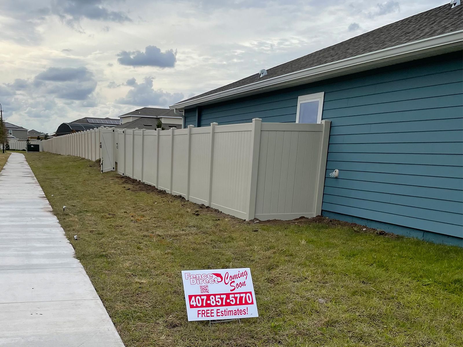 A white fence is sitting next to a blue house.