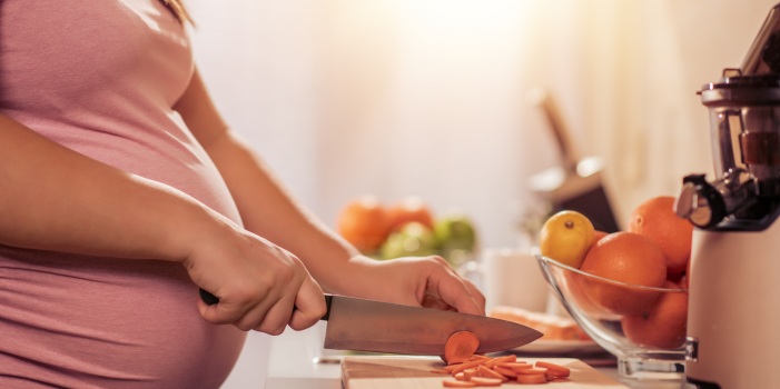 Pregnant Women cutting up carrots to make a healthy meal