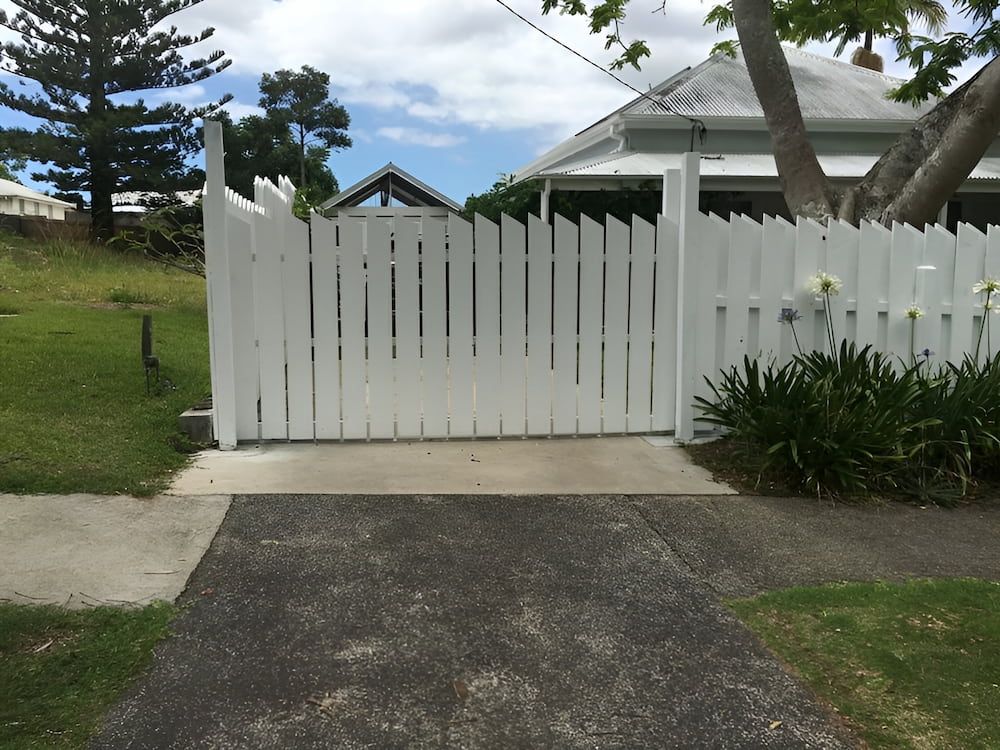 A White Picket Fence Is In Front Of A House — Brunswick Valley Door Centre in Main Arm, NSW