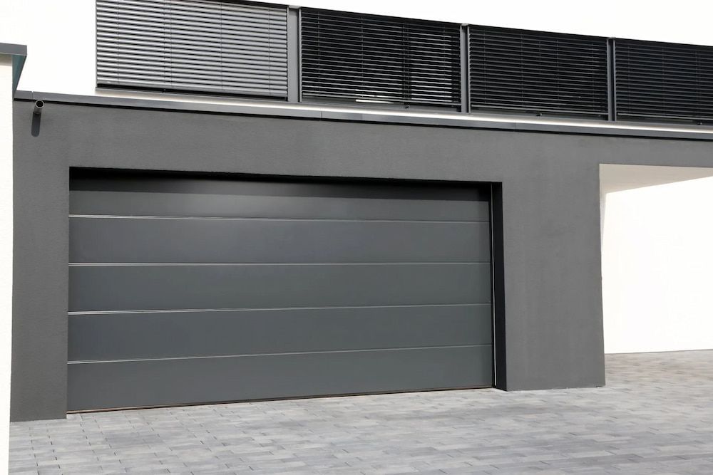 A Gray Garage Door Is Sitting On The Side Of A Building — Brunswick Valley Door Centre in Main Arm, NSW