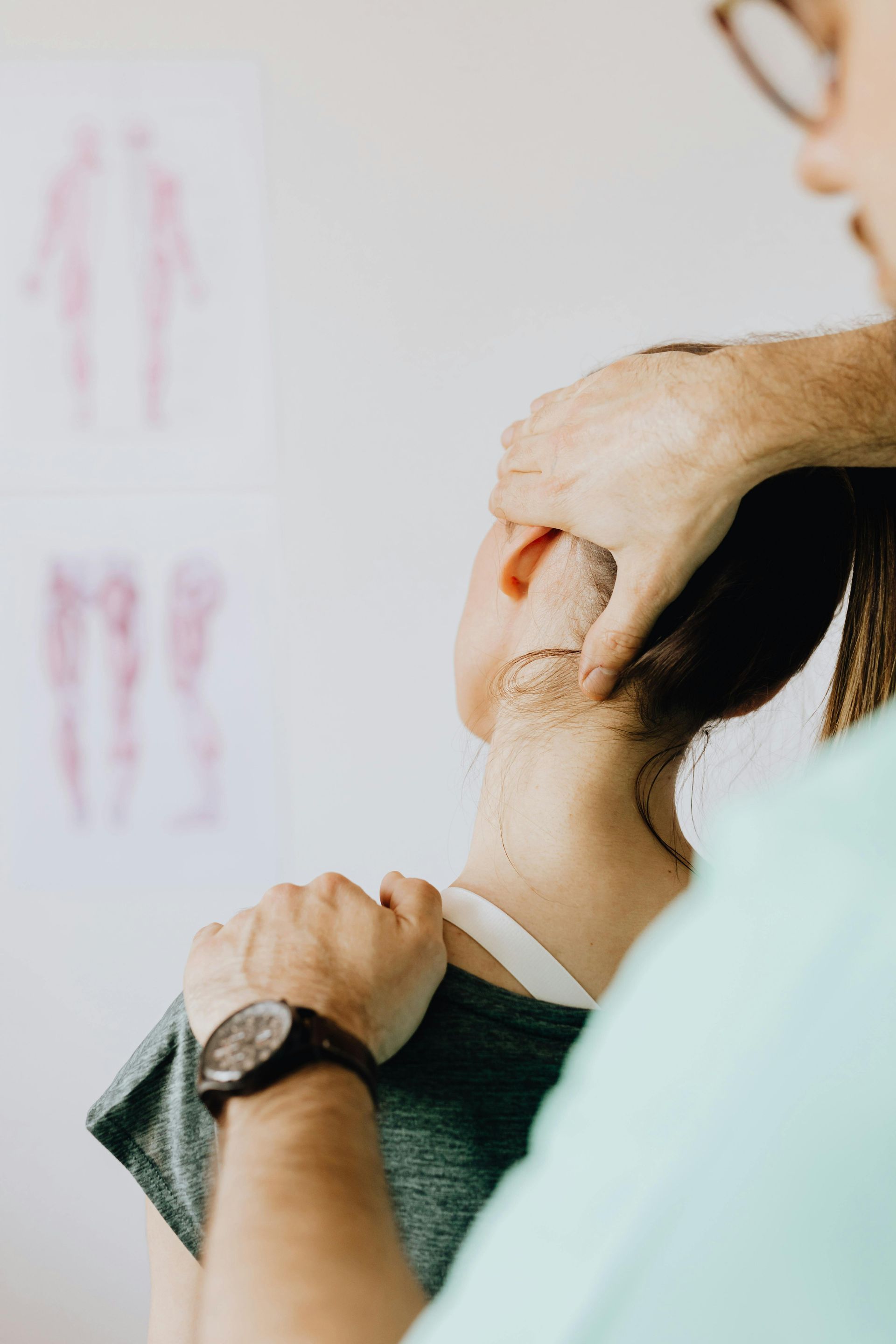 A physical therapist performs a cervical spine adjustment on a patient in a clinical setting.