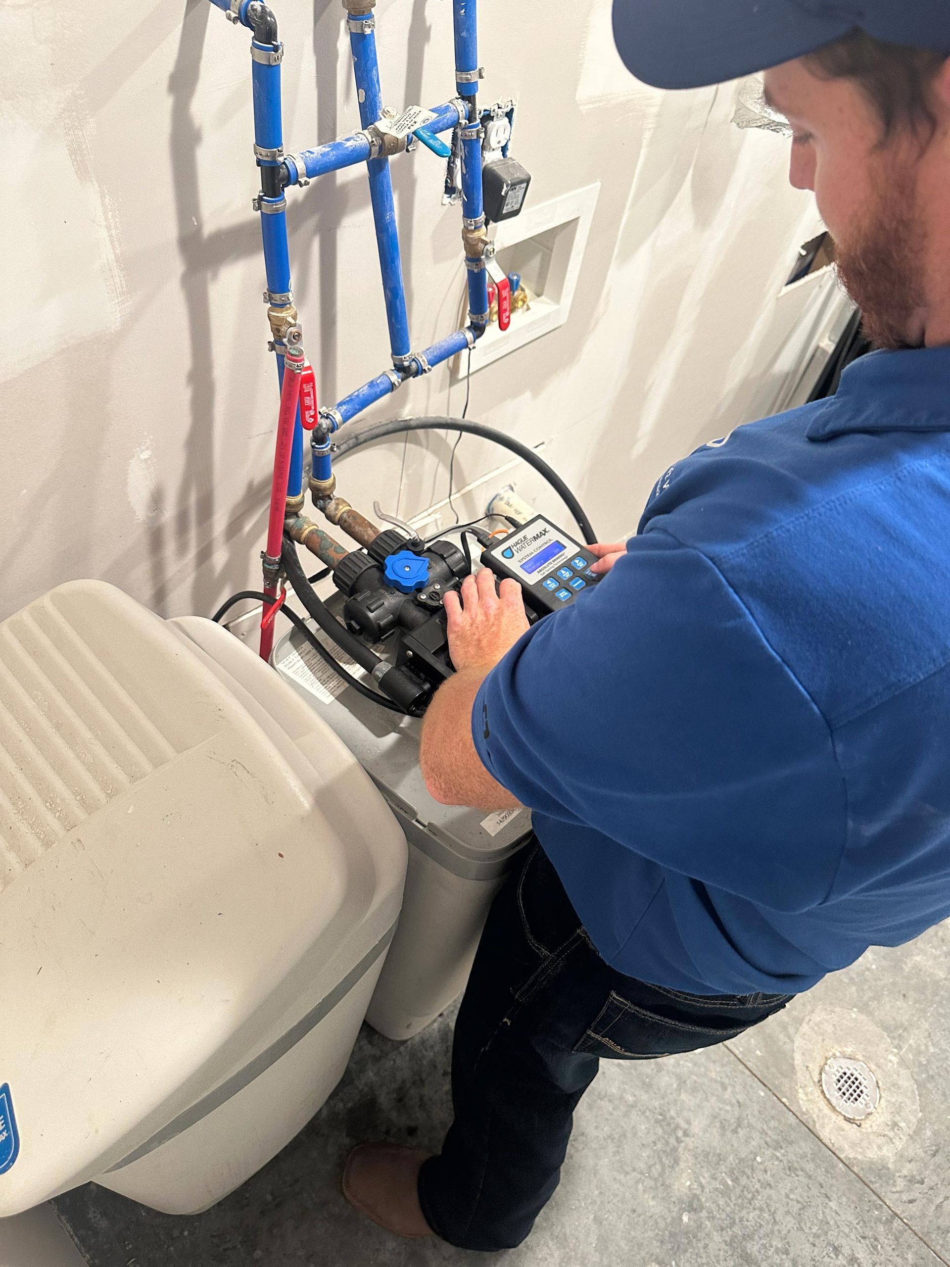 Plumber repairing a toilet tank with exposed pipes in a small bathroom
