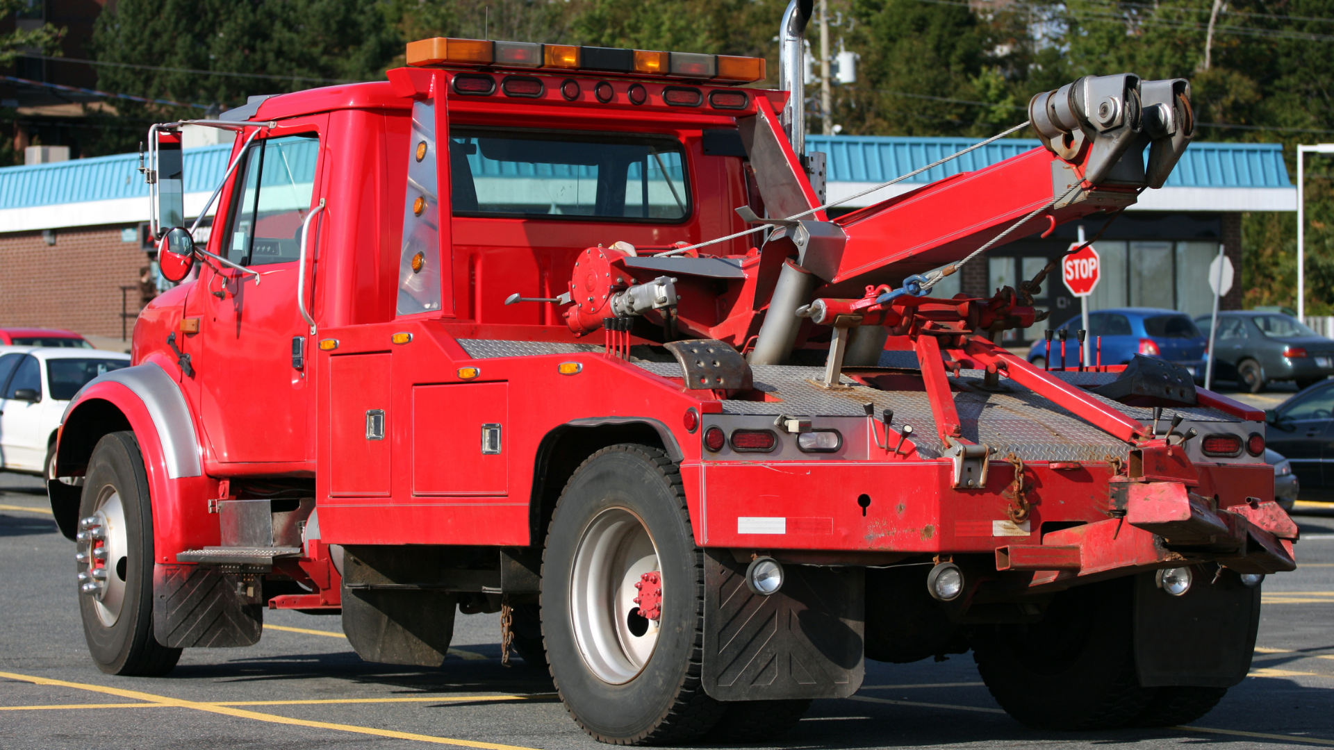 A red tow truck is parked in a parking lot