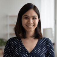 A woman in a blue polka dot shirt is smiling for the camera.