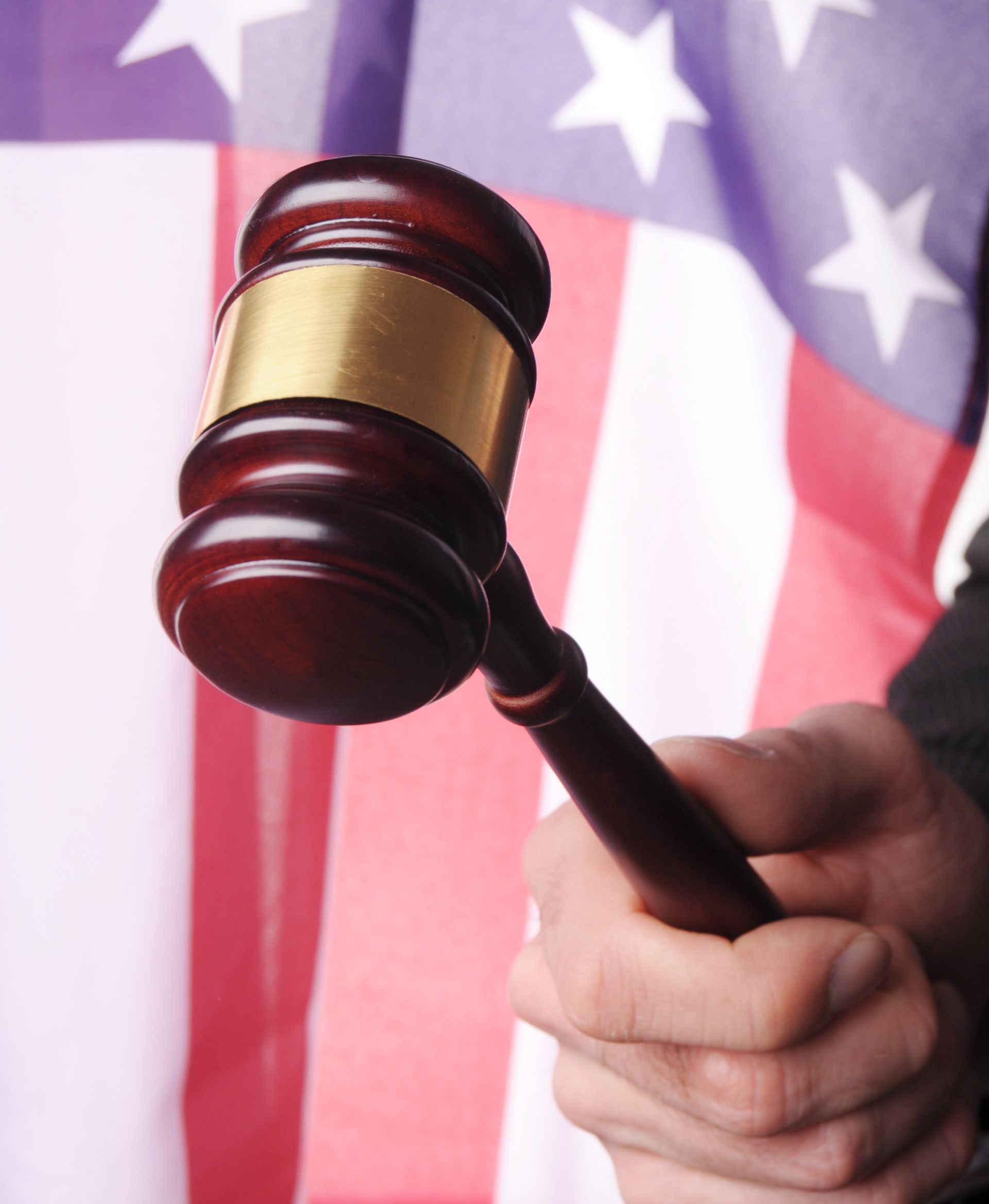 Gavel in hand against an American flag.