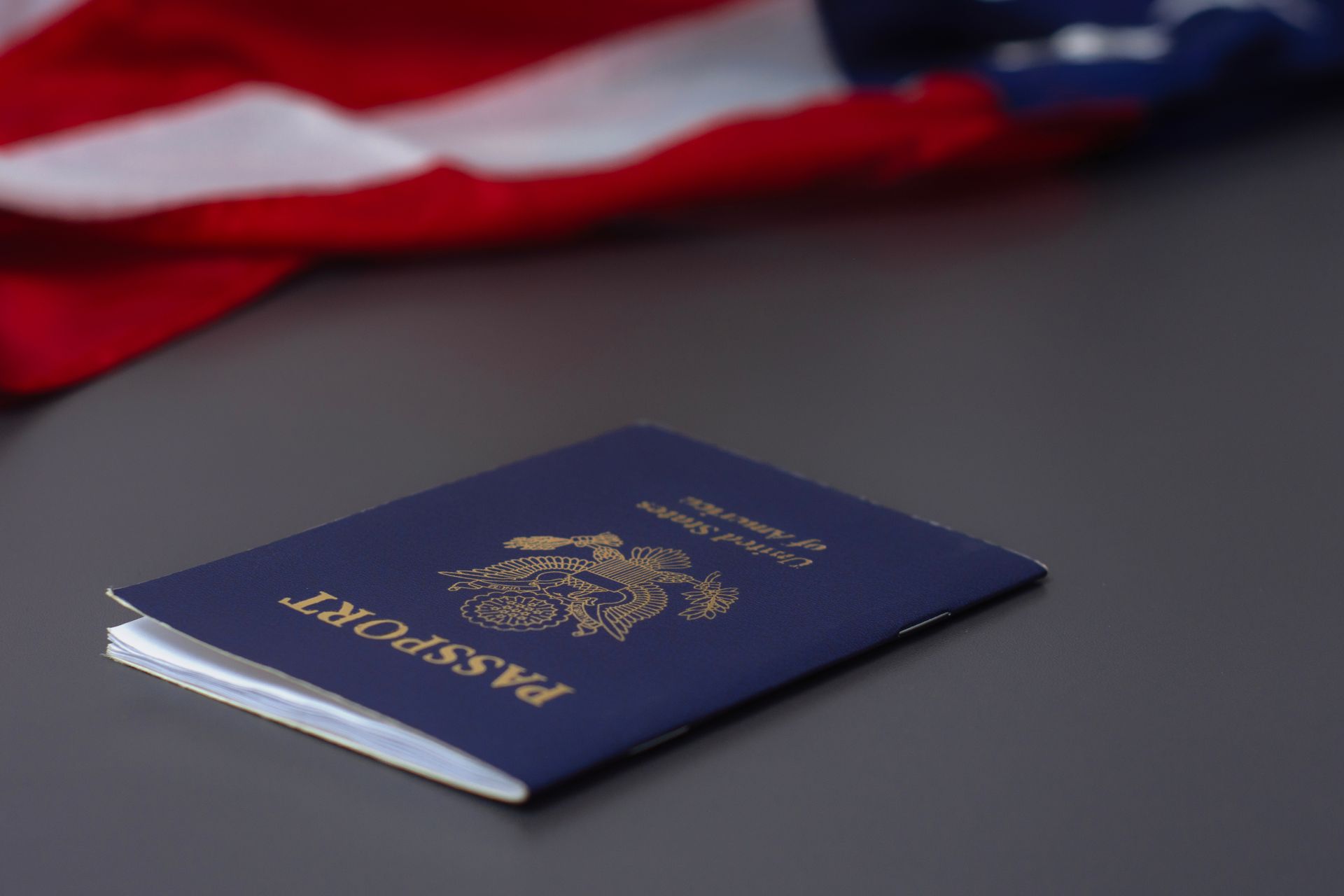 A passport is sitting on a table in front of an american flag.