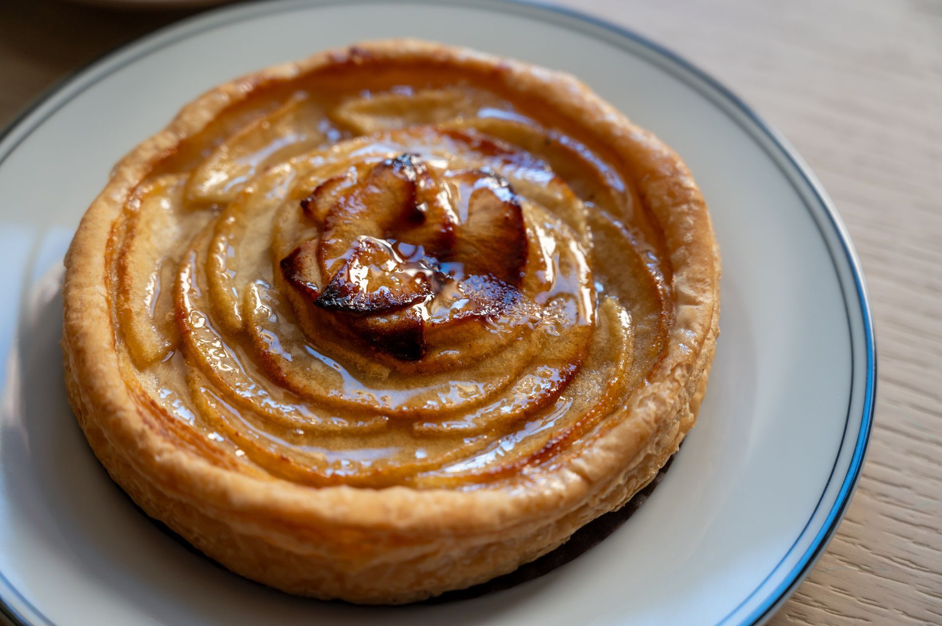 An apple pie is on a white plate on a table.