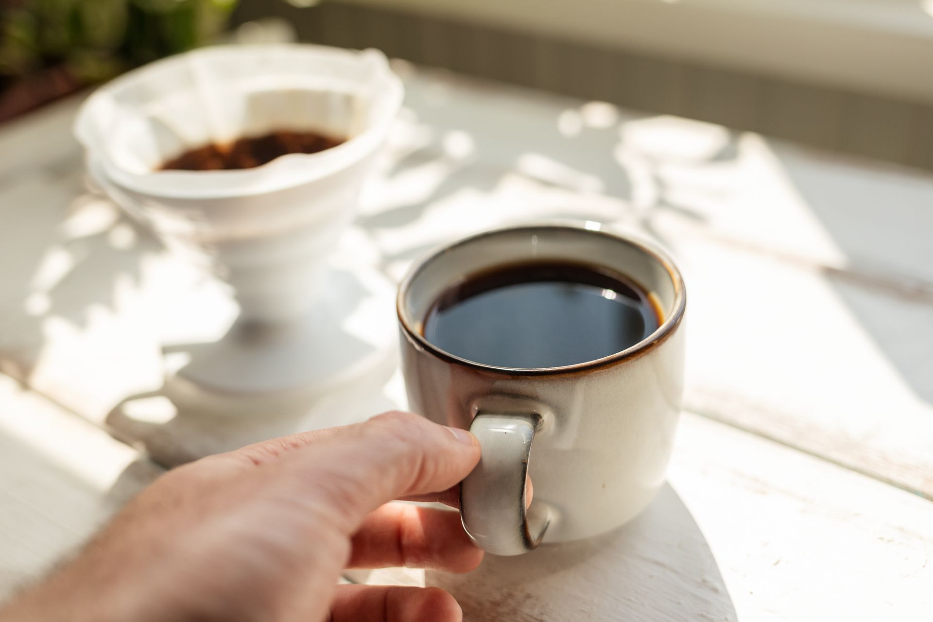 A person is holding a cup of coffee on a table.
