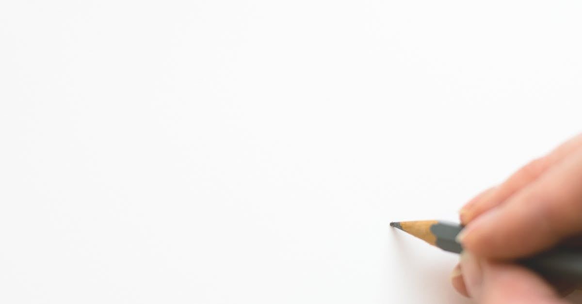 Hand holding a pencil poised over a blank white page