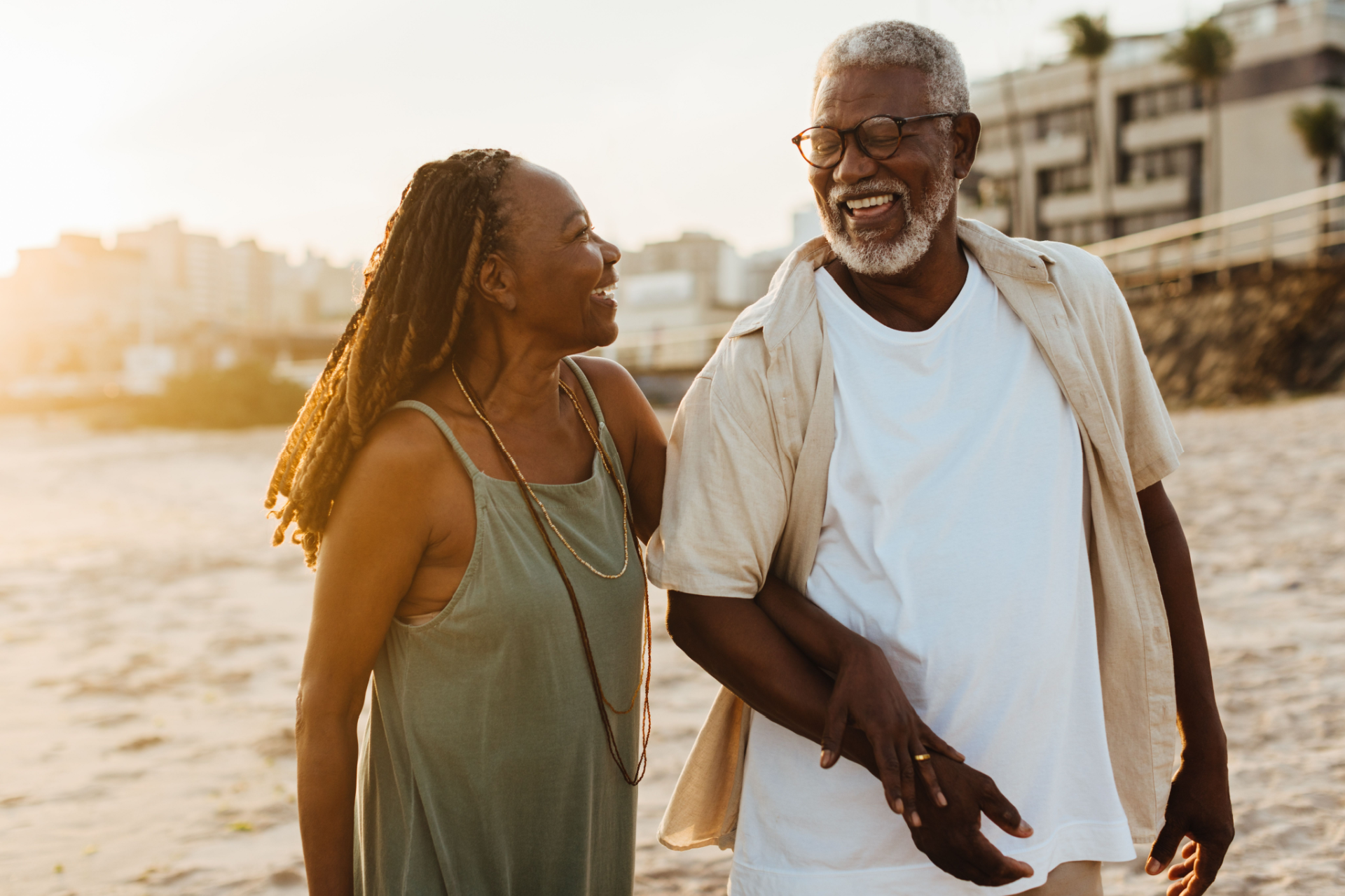 a man and woman walking on the beach holding hands
